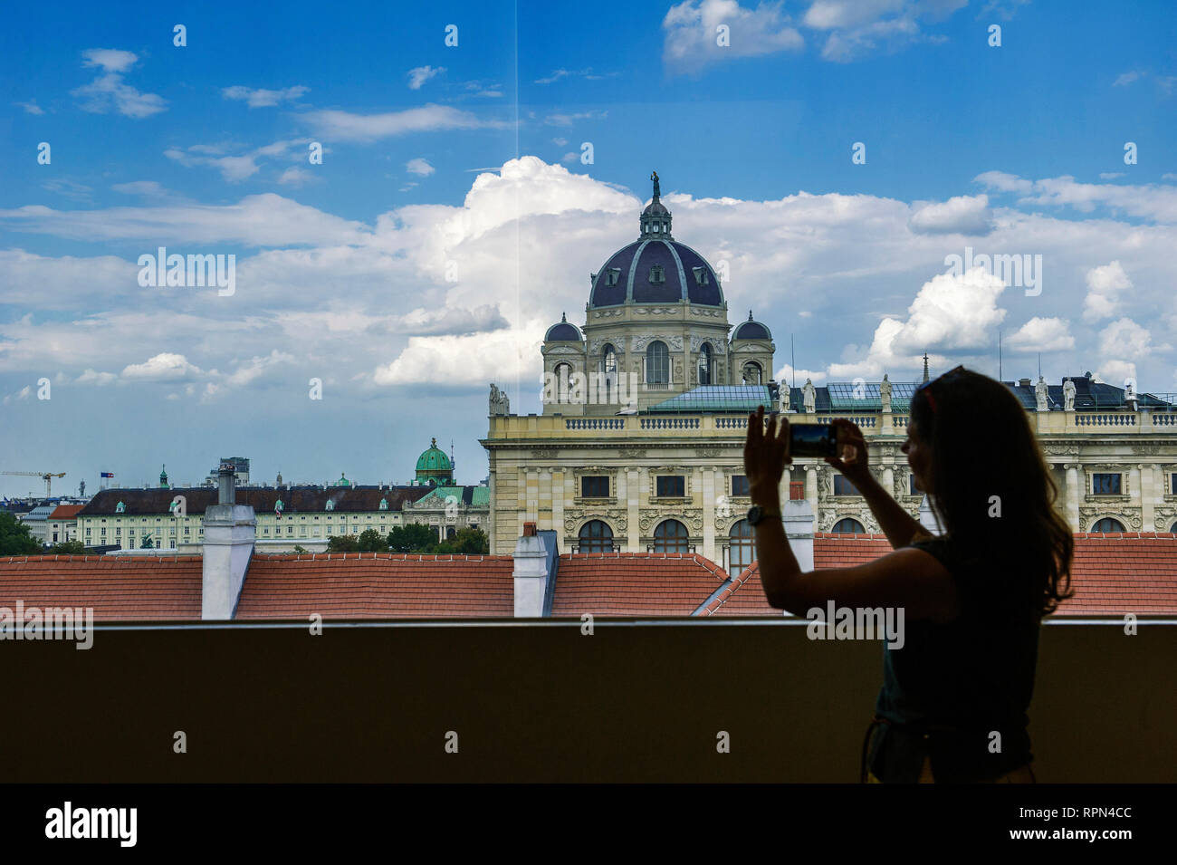 Giovane donna di scattare una foto con il suo telefono cellulare la vista del Kunsthistorisches Museum da una finestra all'interno di Leopold Museum, Vienna, Austria Foto Stock
