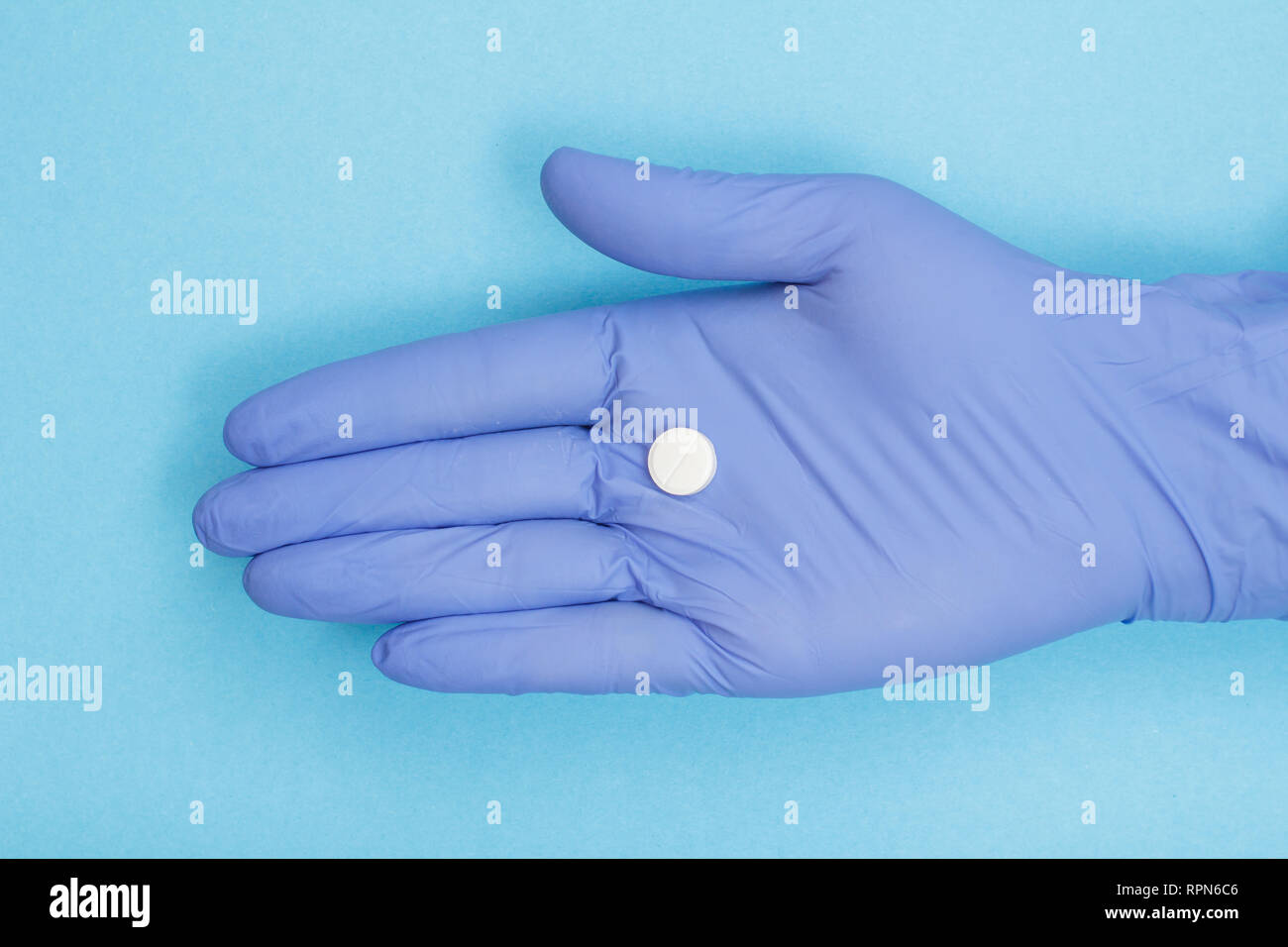 Vicino la mano del medico donna in blu guanto in lattice con pillola bianco sul palmo della sua mano. Legal drug store concept. Foto Stock