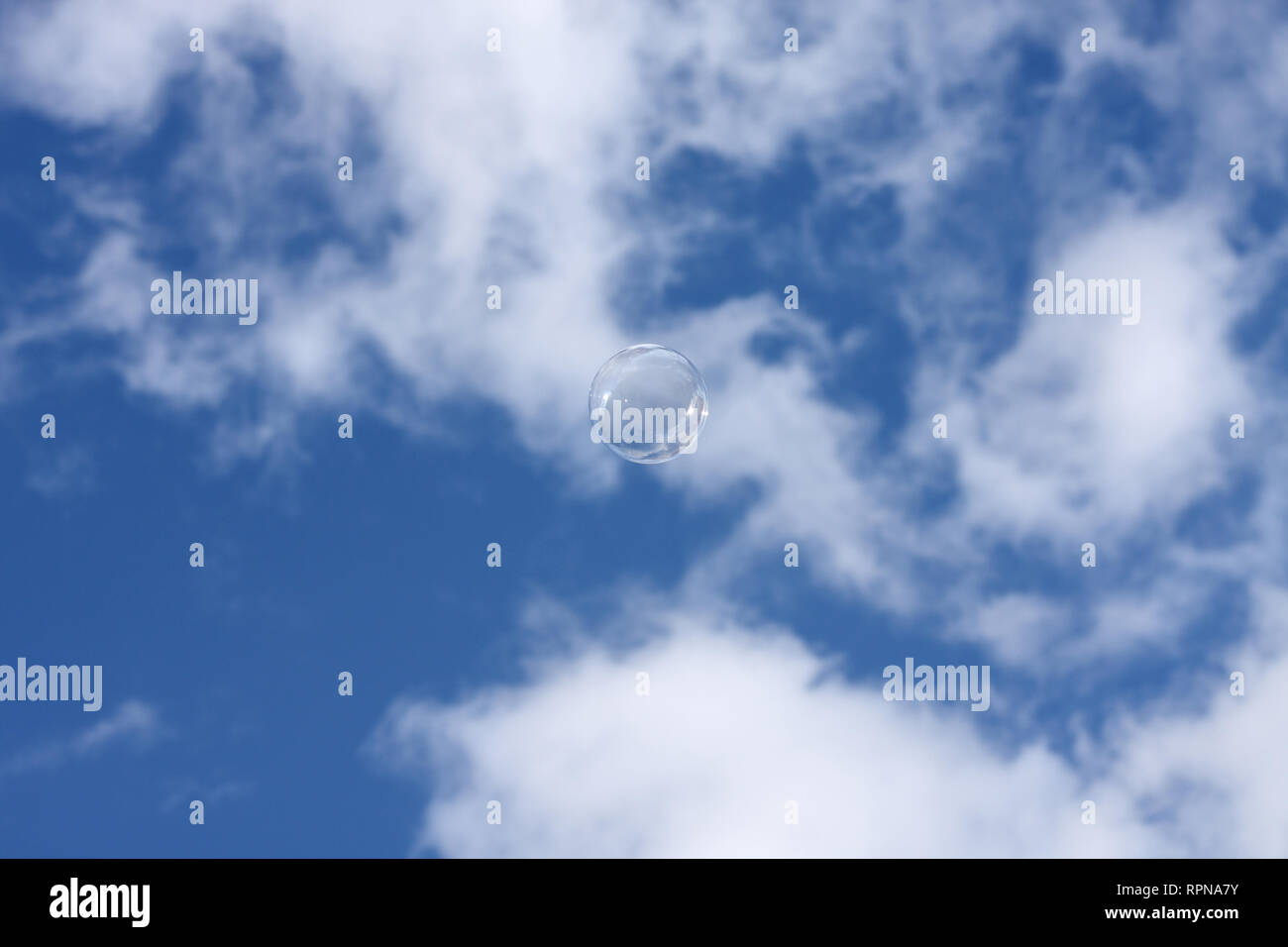Una singola bolla galleggianti contro un nuvoloso cielo blu Foto Stock