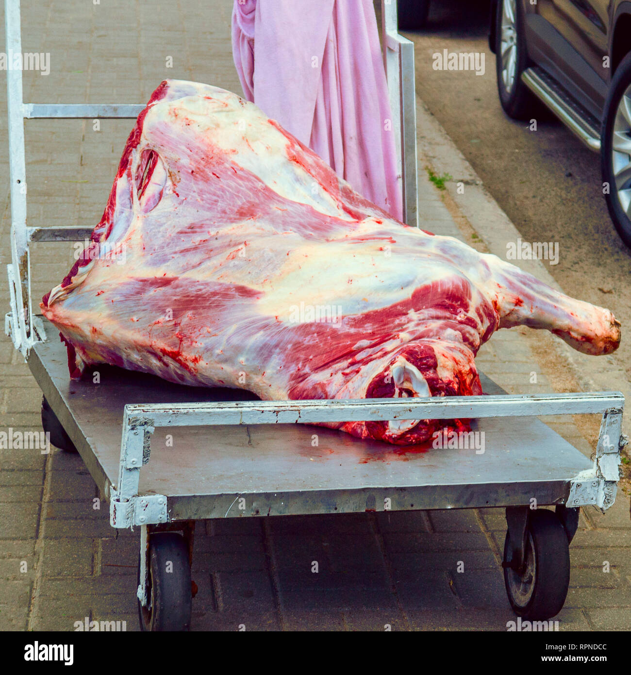 Grande, carcassa fresca di carne si trova su un carrello su strada Foto Stock