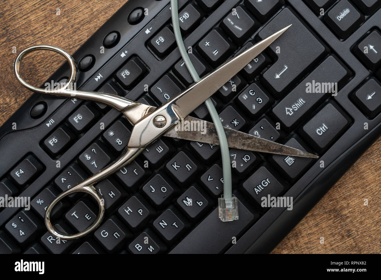 Il taglio a forbice cavo internet sulla tastiera del computer. Prevenzione del furto di dati, informazioni via Internet. Foto Stock