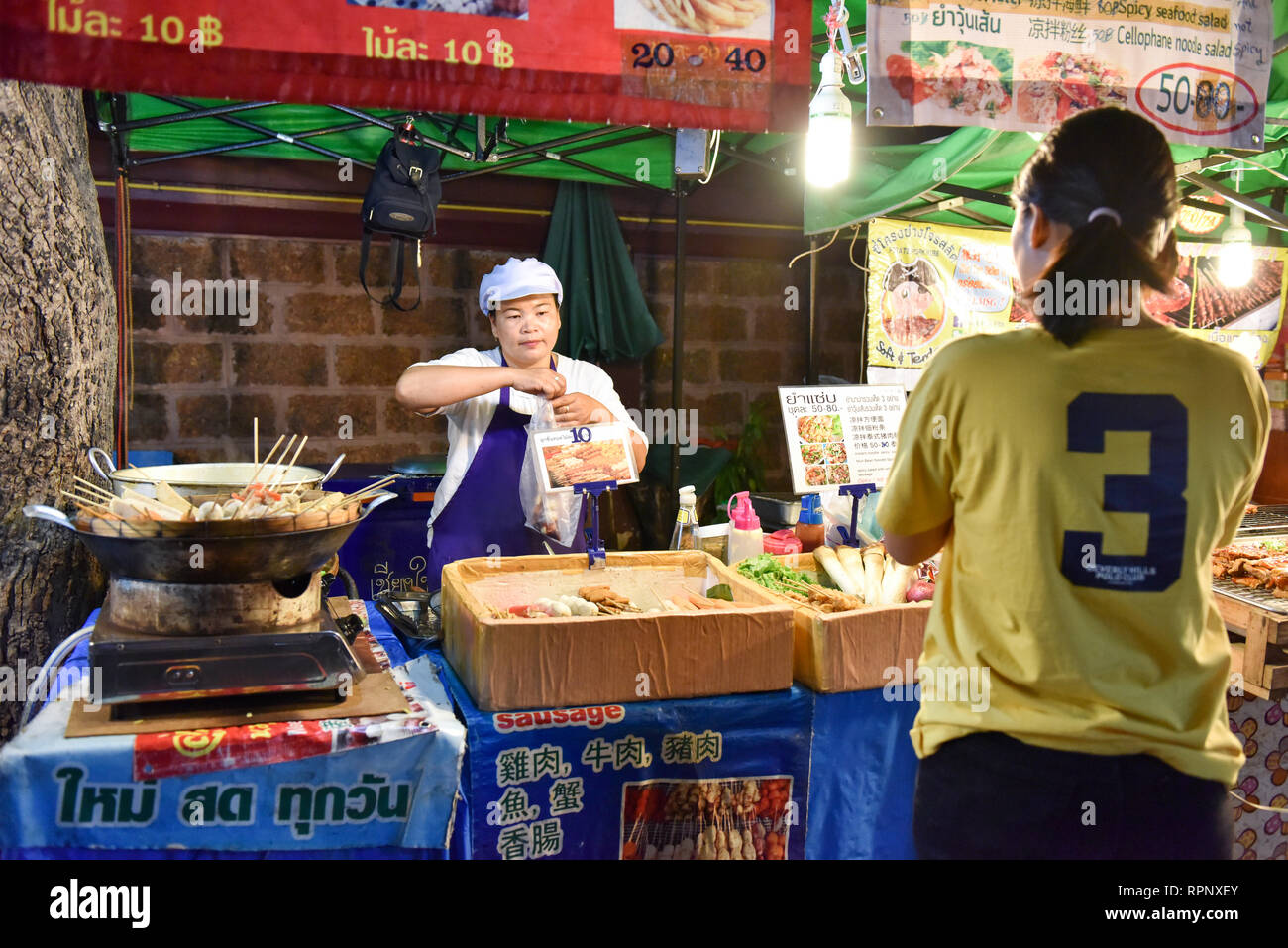 Fornitore di cibo di strada a piedi domenica Mercato , Chiang Mai, Thailandia Foto Stock