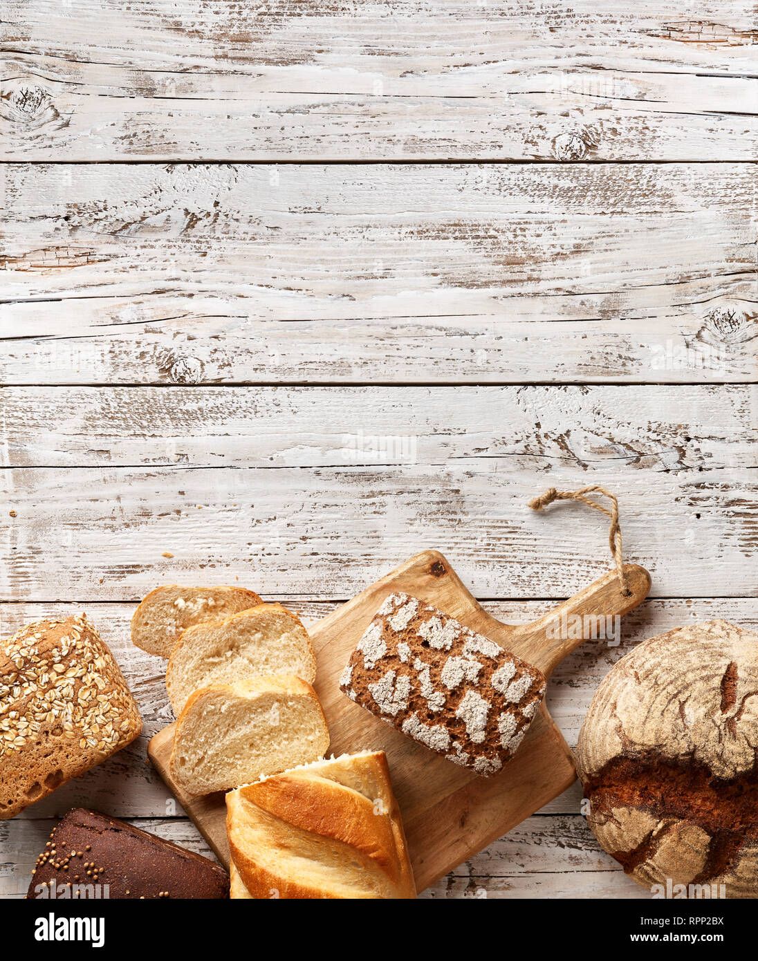 Assortimento di pane fresco su un sfondo di legno. Il bianco e il pane di segale in un sacchetto di carta. Concetto di panetteria con posto di copia Foto Stock