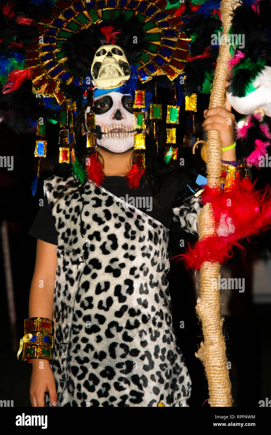 Ragazzo giovane pesantemente camuffata con piume colorate e maya skull mask, indossando il costume di leopard, stando in piedi in strada durante il messicano annuale cele Foto Stock