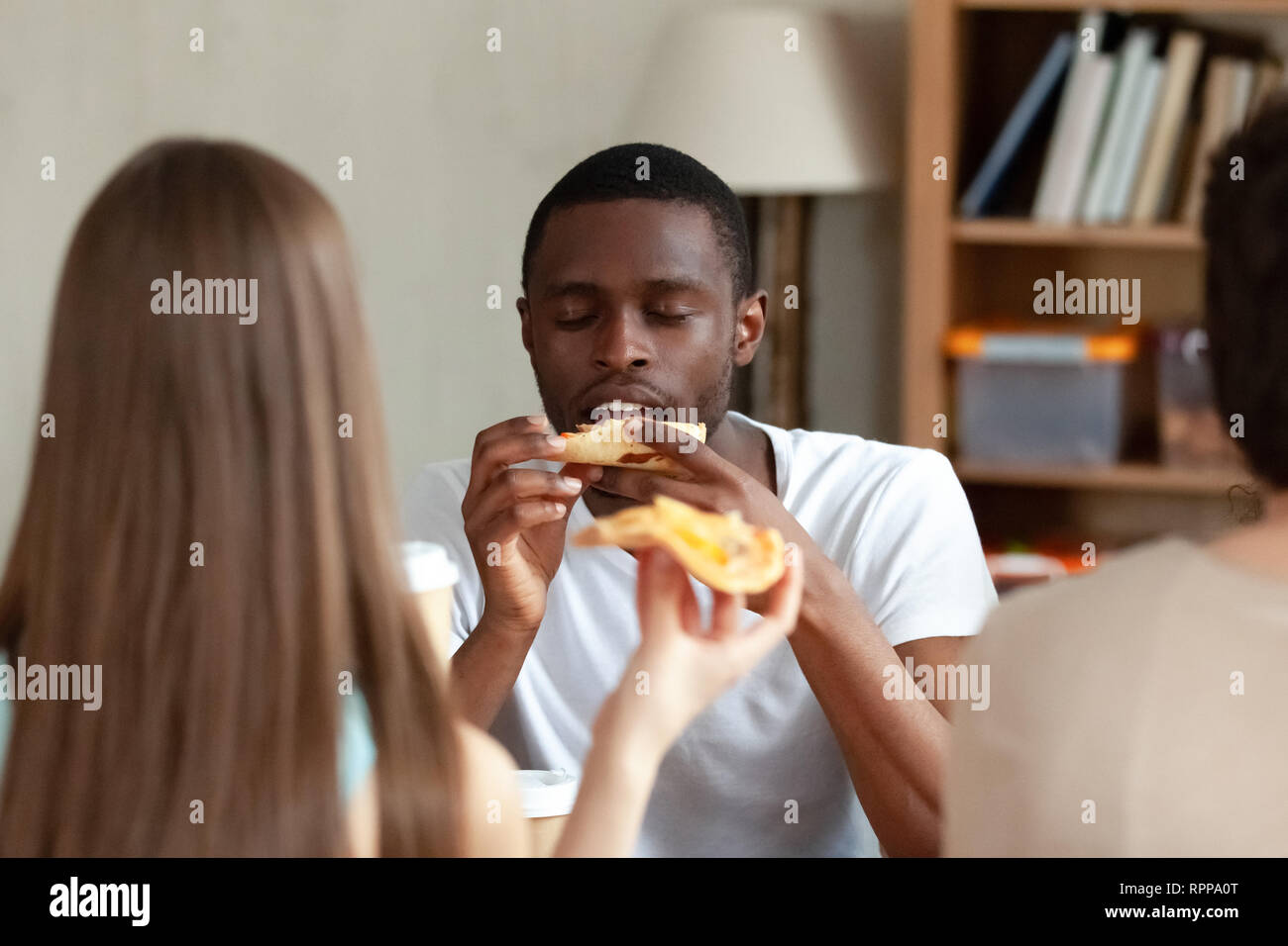 Felice African American uomo godendo la pizza con gli amici Foto Stock
