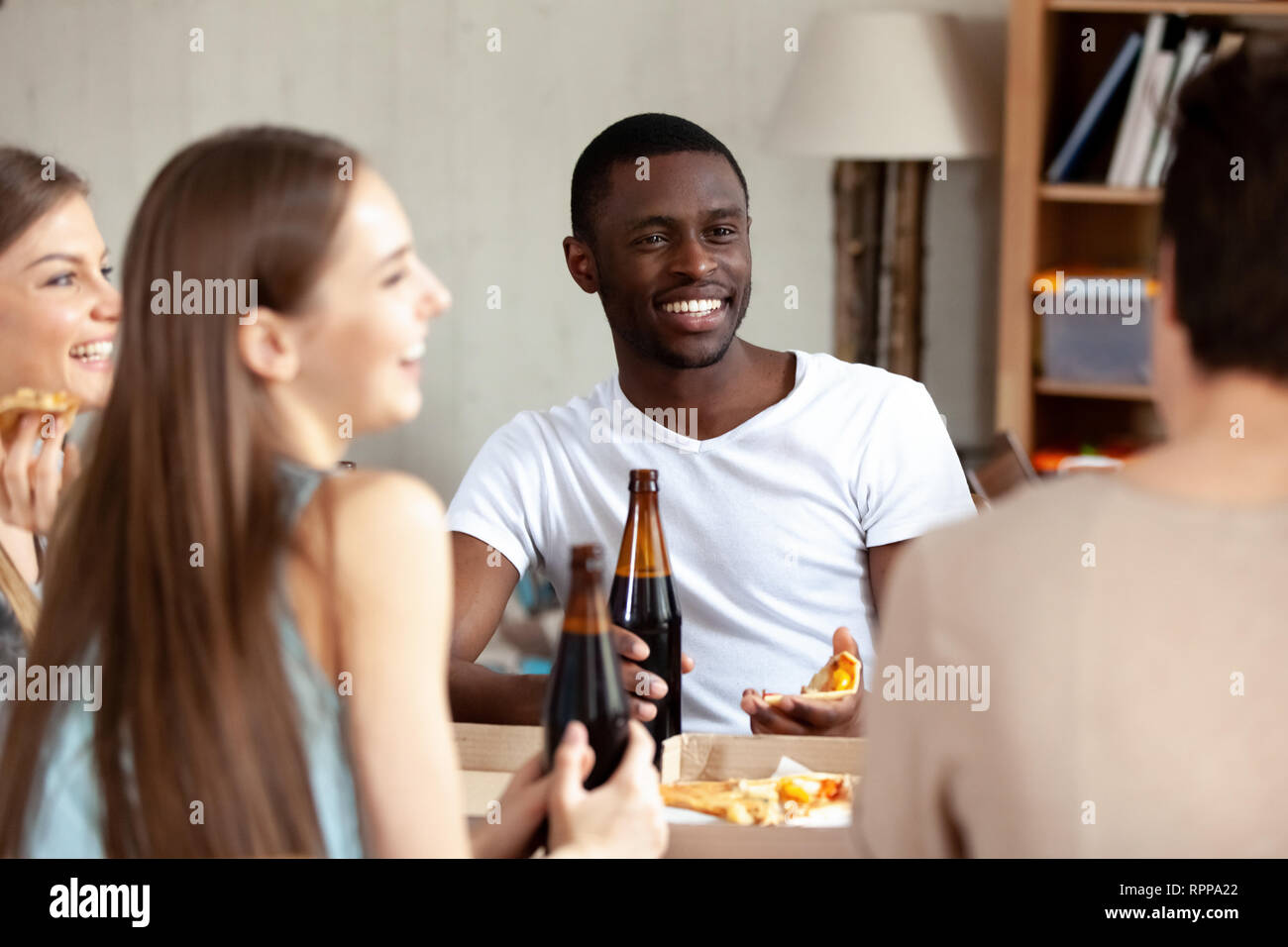 Sorridente African American uomo a bere birra con gli amici in pizzeria Foto Stock