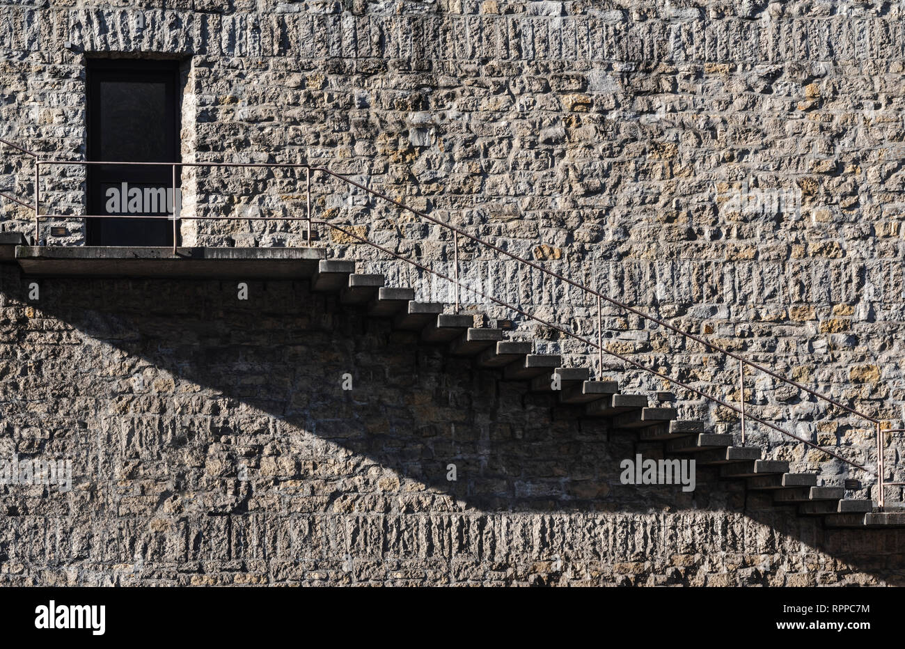 Immagine minima di una scala esterna e porta su un muro di pietra edificio. Architettura d'epoca in un concetto minimalista. Foto Stock