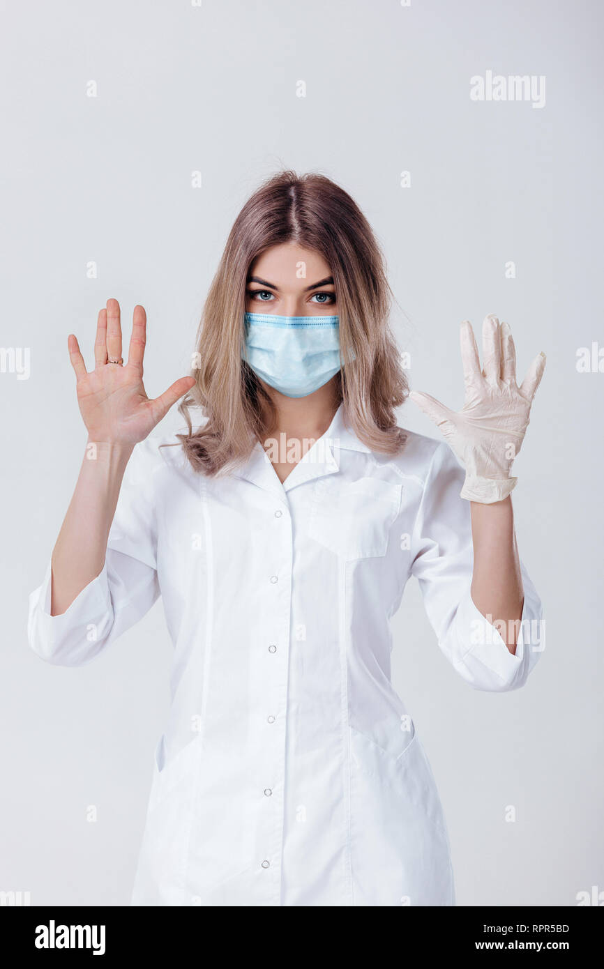 Ritratto di donna medico con una maschera facciale medico mostra le mani. una mano e l'altra senza Foto Stock