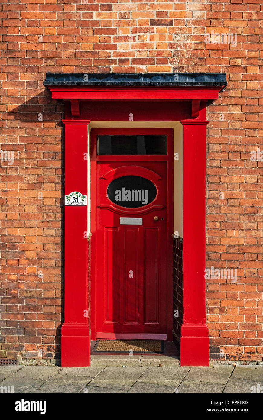 Vista dettagliata del 1950 - 60's Rosso porta anteriore con finestra ovale e portico su un rosso casa in mattoni in luogo di mercato, Tickhill nel Metropolitan Borough di Don Foto Stock