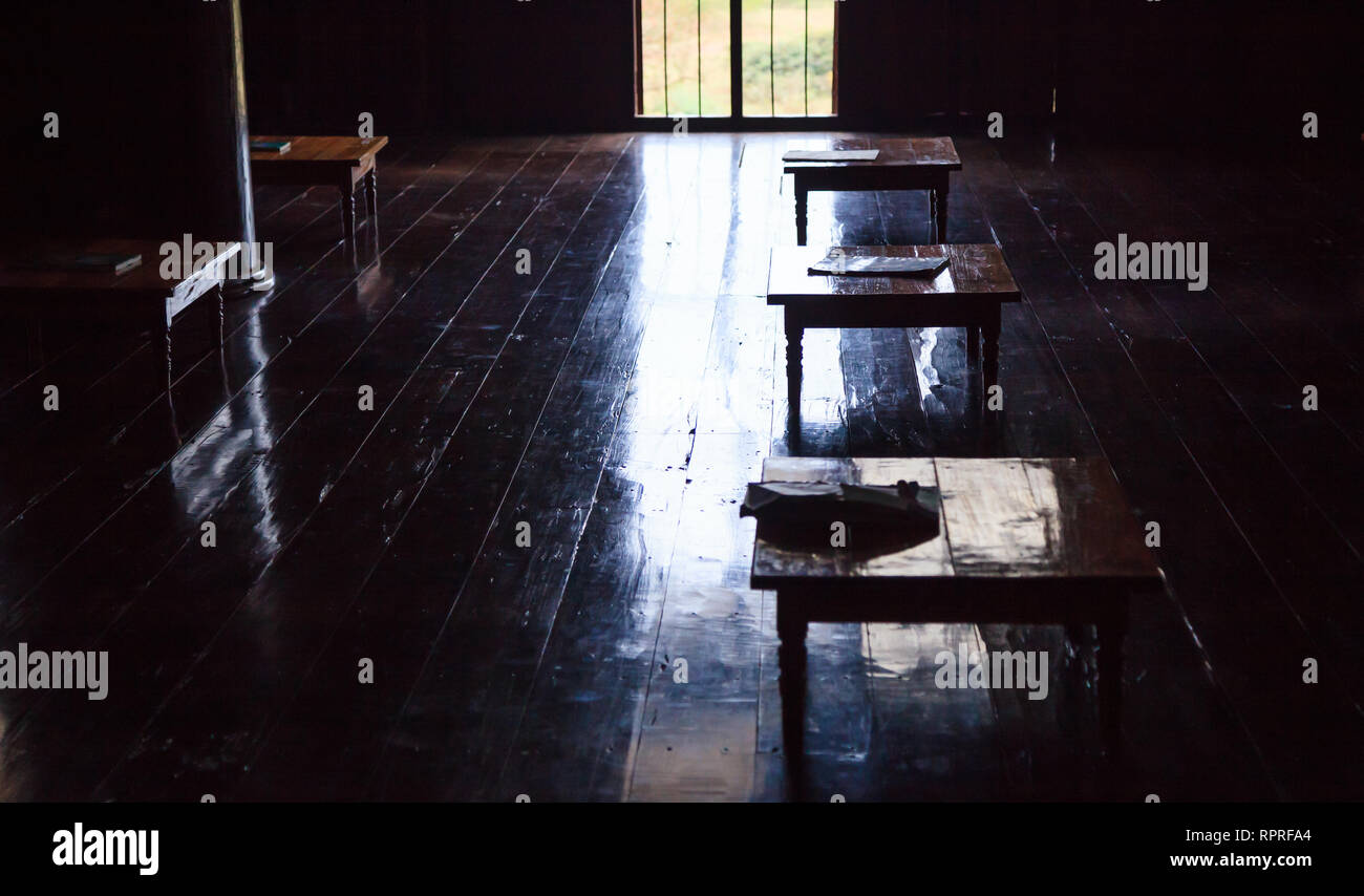 Educazione rurale nei paesi in via di sviluppo, la sala studio all'interno pieno con piccole scrivanie in legno, senza i moderni dispositivi laccato su pavimento in legno. Auto Sufficienc Foto Stock