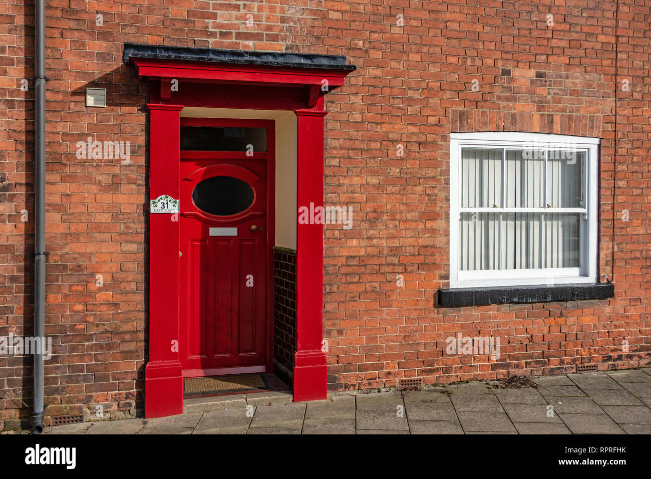 Vista dettagliata del 1950 - 60's Rosso porta anteriore con finestra ovale e portico su un rosso casa in mattoni in luogo di mercato, Tickhill nel Metropolitan Borough di Don Foto Stock