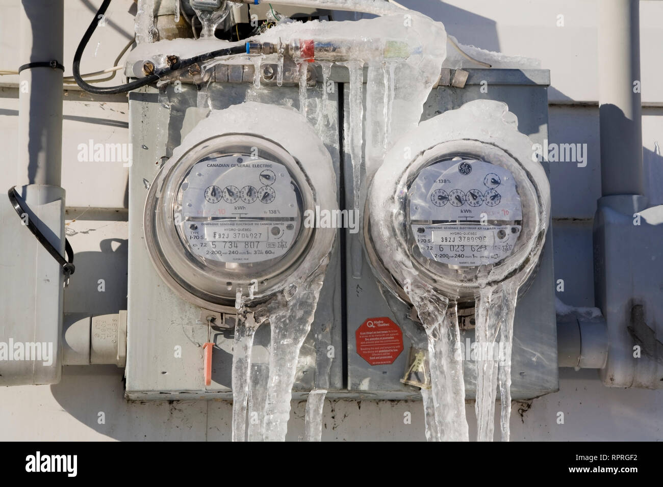 Close-up di ghiaccio coperto idro il consumo di elettricità di metri sulla parete esterna di una casa residenziale in inverno Foto Stock