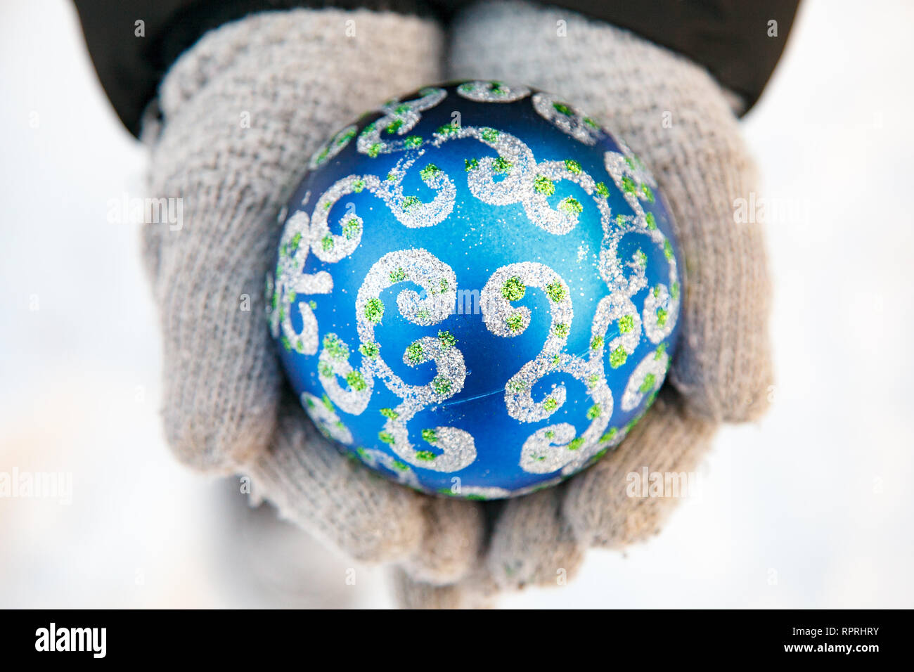 Due mani hanno un blu ornamento di Natale. Abbracciando lo spirito della stagione. Semplice ed elegante. Foto Stock