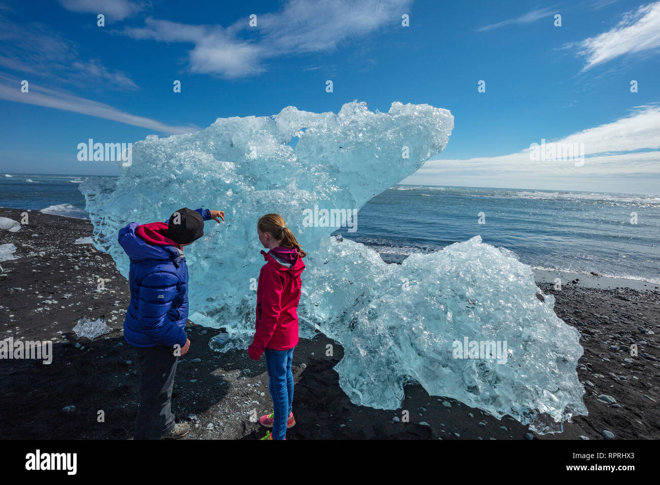 Persone esaminando iceberg Breidamerkursandur sulla spiaggia di sabbia nera, al di sotto di Jokulsarlon. Sudhurland, sud est dell'Islanda. Foto Stock