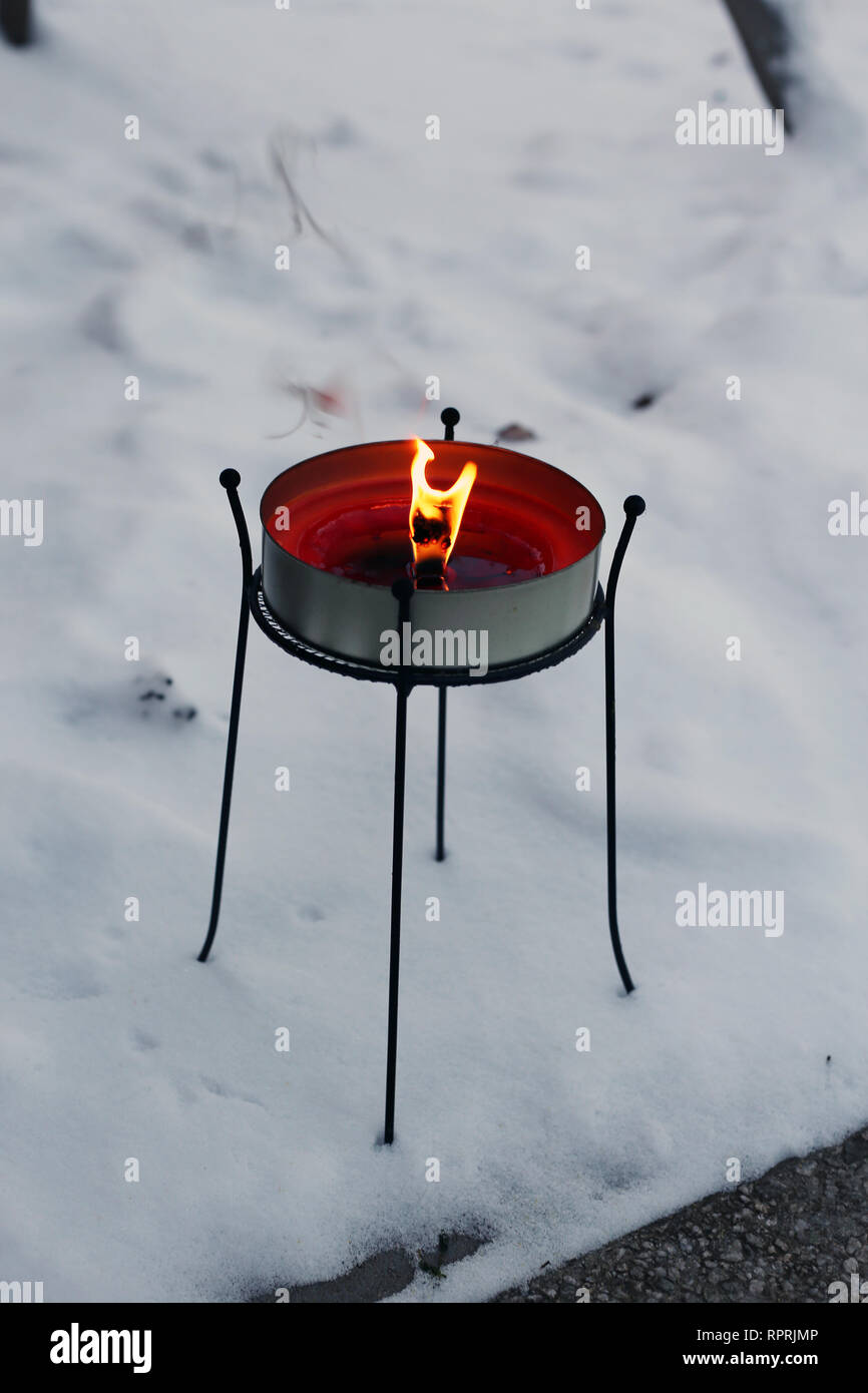 Grande candela rossa bruciare con una grande fiamma. Fotografato all'aperto durante un freddo inverno nevoso giorno in Finlandia. Bella casa decor e l'elemento. Foto Stock
