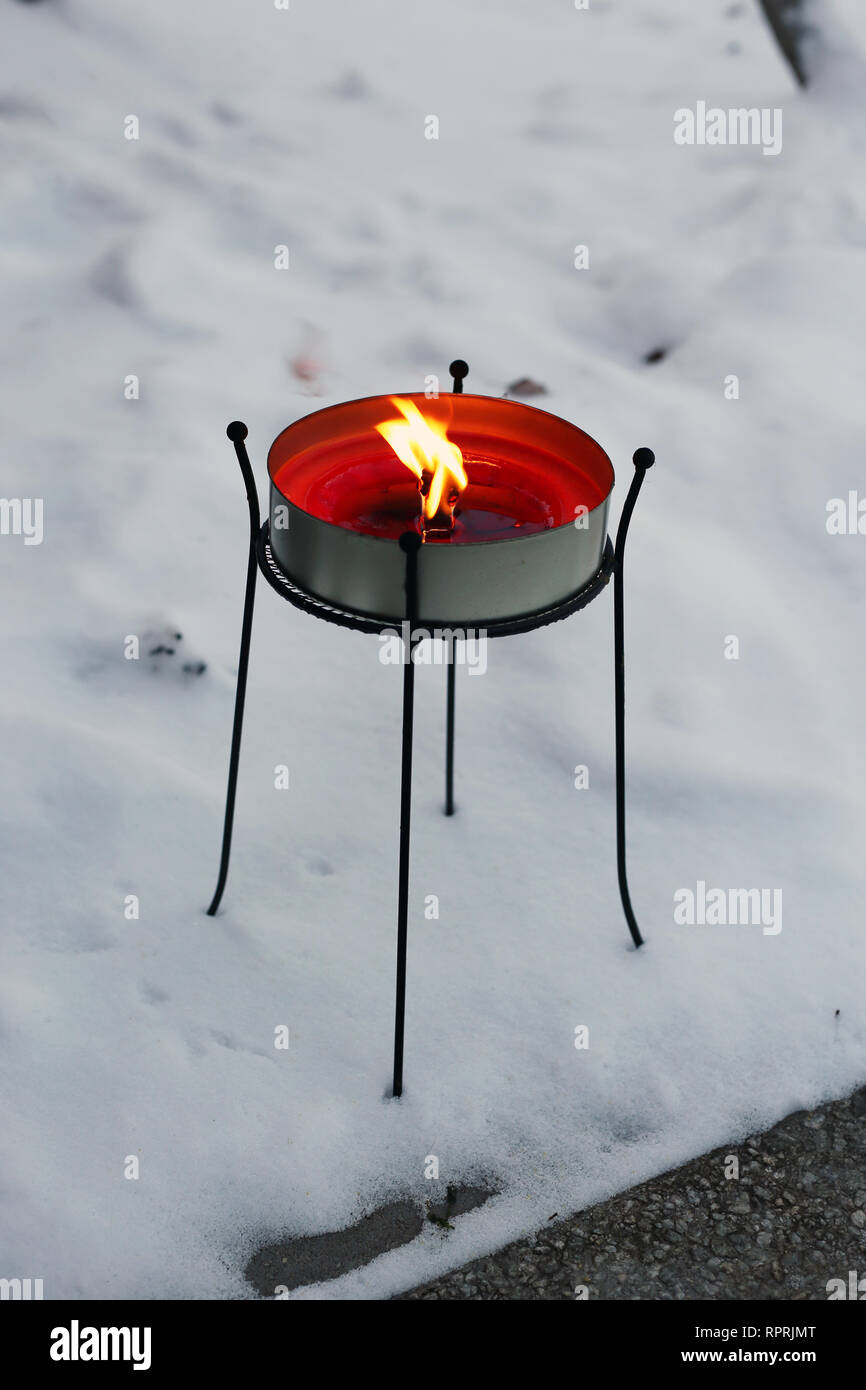 Grande candela rossa bruciare con una grande fiamma. Fotografato all'aperto durante un freddo inverno nevoso giorno in Finlandia. Bella casa decor e l'elemento. Foto Stock