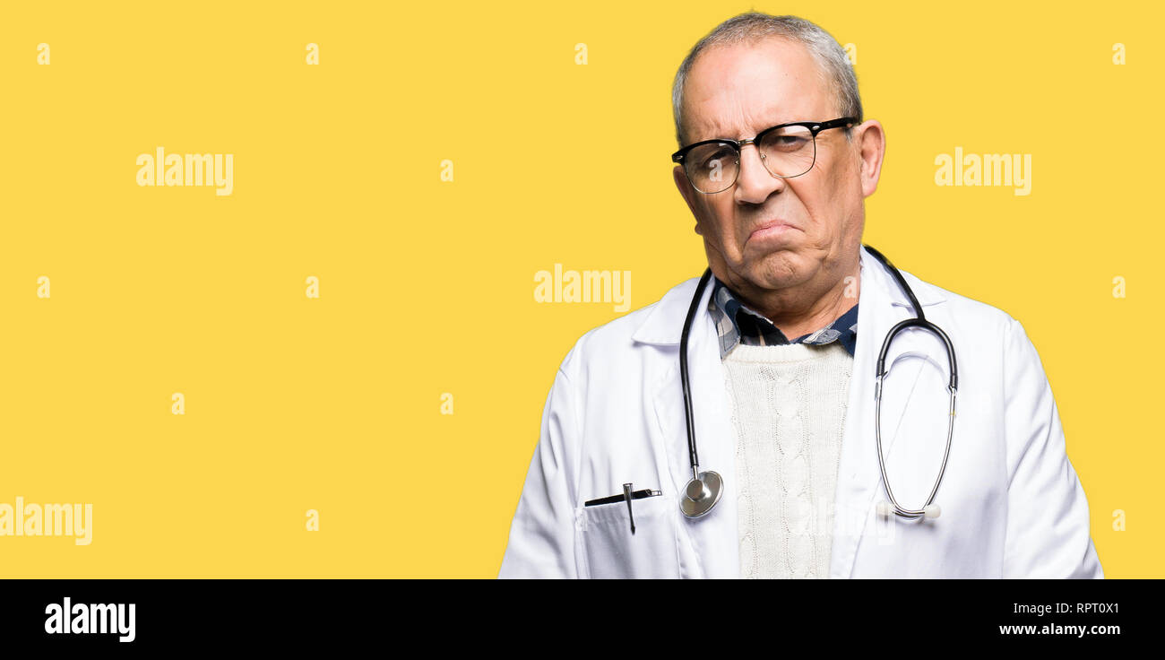 Bello il senior medico uomo indossa cappotto medico premuto e la preoccupazione per la sofferenza, gridando arrabbiato e paura. Triste espressione. Foto Stock