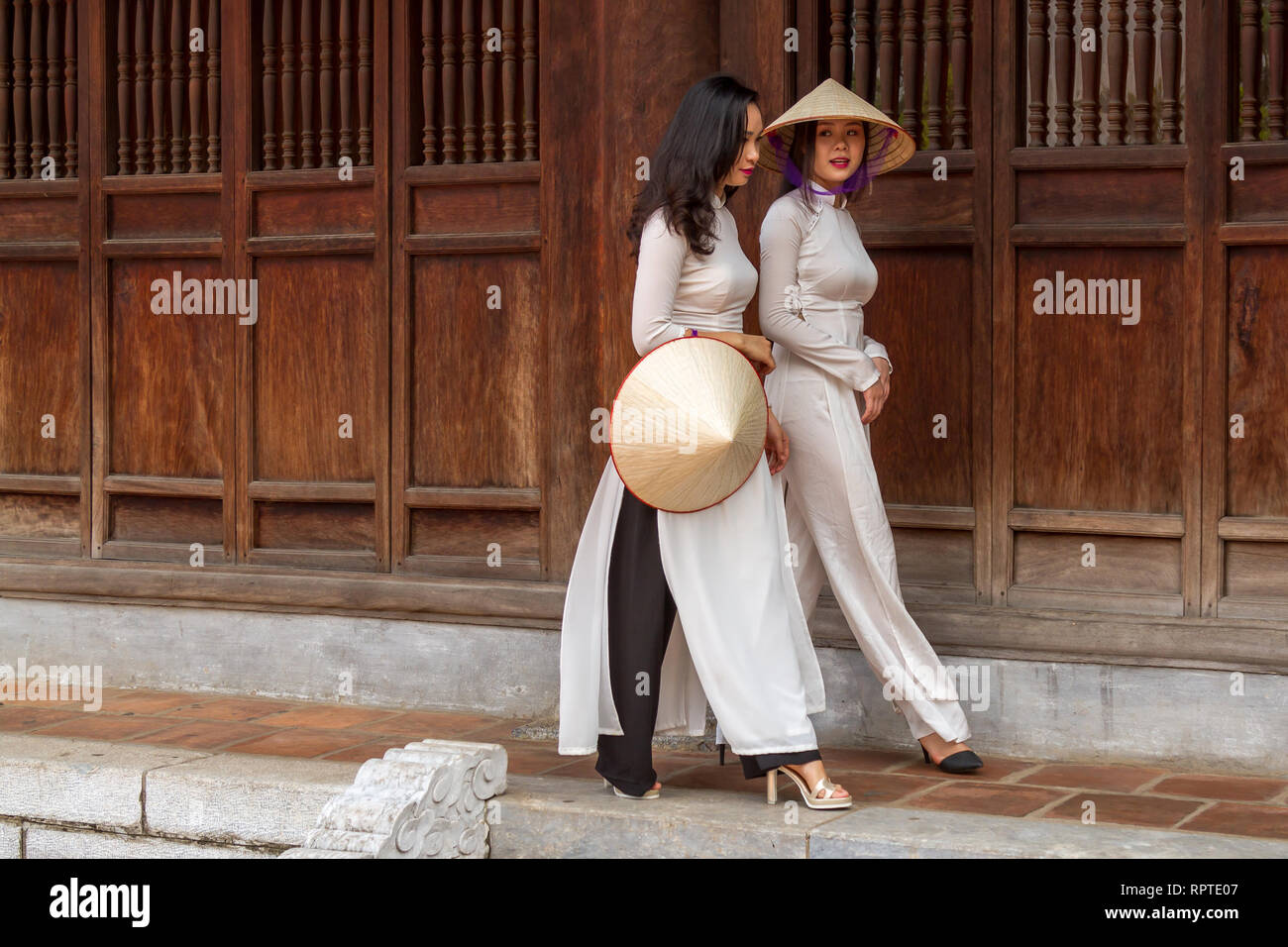 Giovane vietnamita le donne che indossano il tradizionale abito Ao IAM e il cappello conico Non La. ubicazione; Tempio della Letteratura ad Hanoi, Vietnam Foto Stock