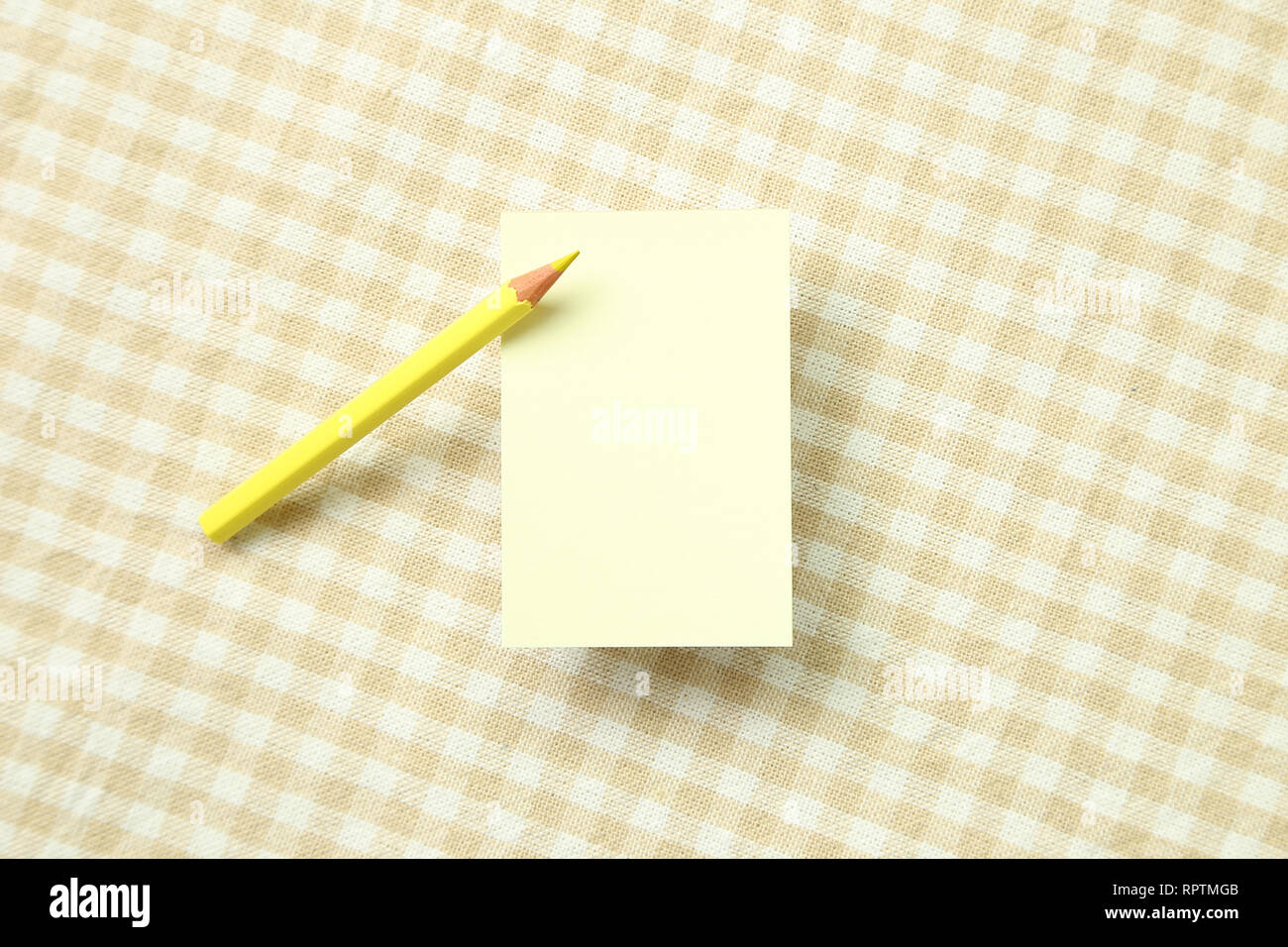 Giallo nota memo pad e colorato in giallo matita su beige modello di controllo sfondo di tessuto Foto Stock