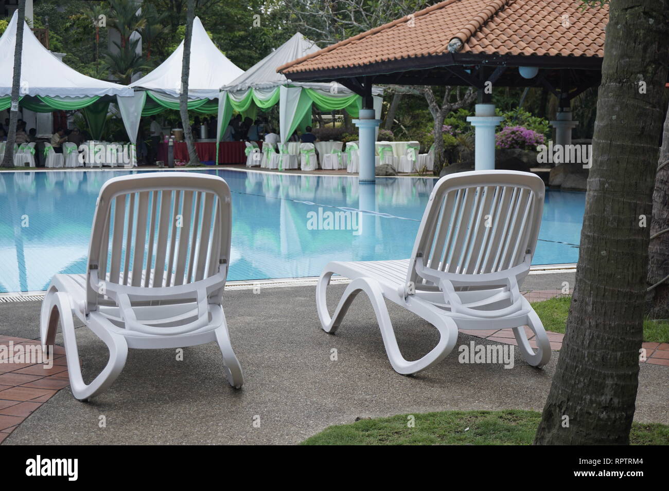 Poltrone bianche in corrispondenza di una piscina Foto Stock