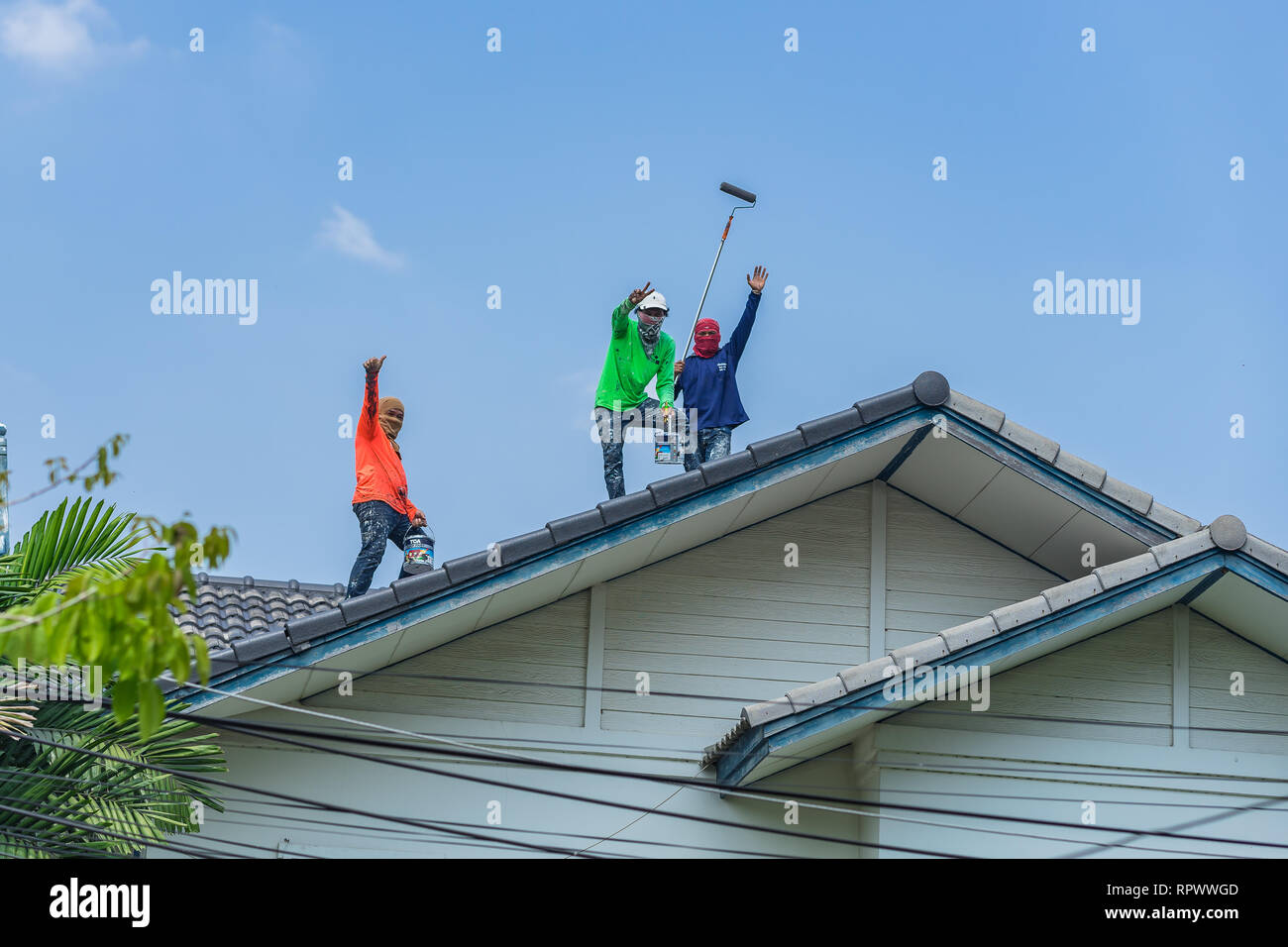 Verniciatura del cielo blu, pittori posa per foto sul tetto di casa. Foto Stock