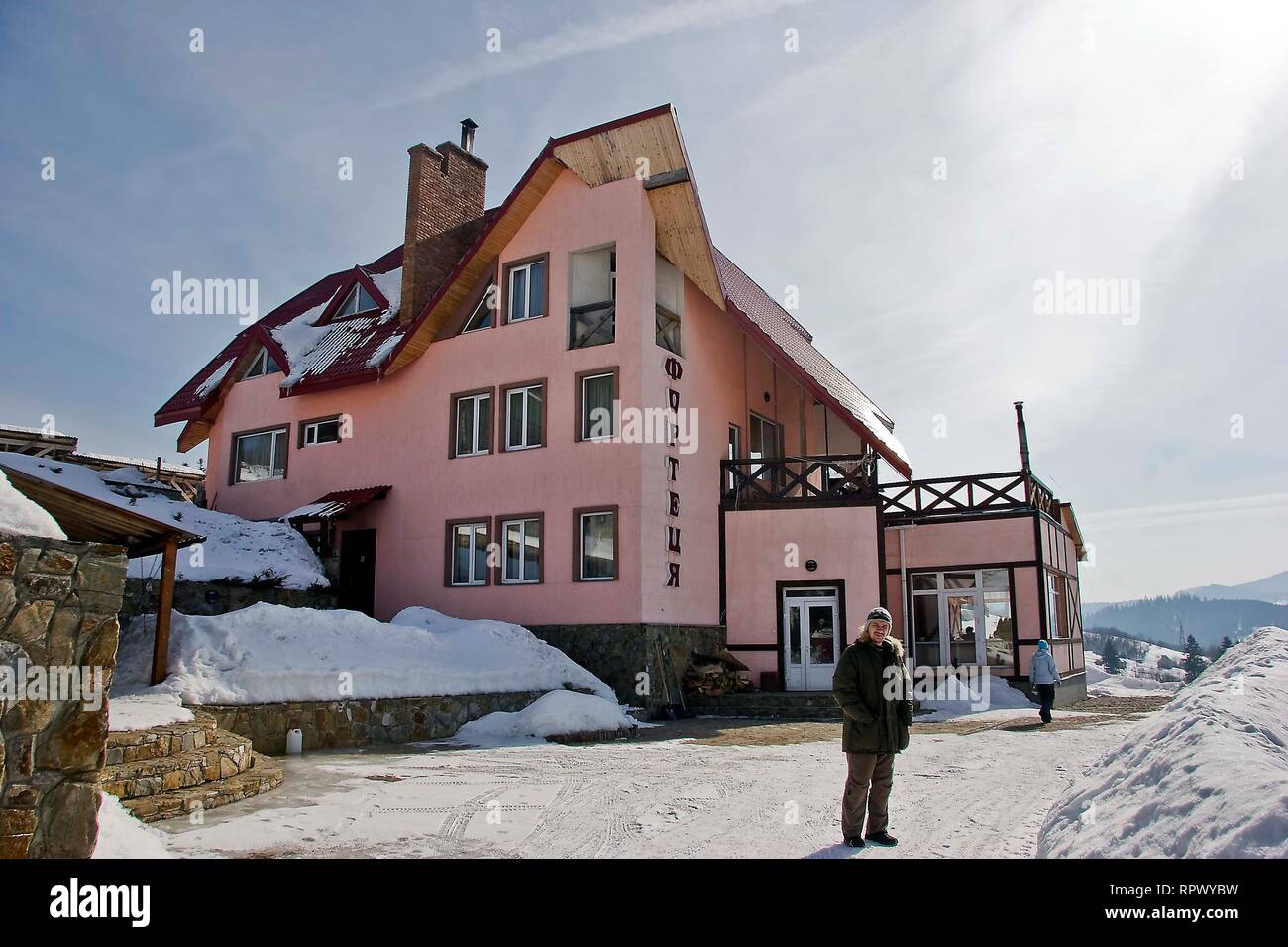 Giornata di sole, vista dalla finestra su un paesaggio innevato. Villaggio di montagna, case e recinzioni in Ucraina dei Carpazi. Foto Stock