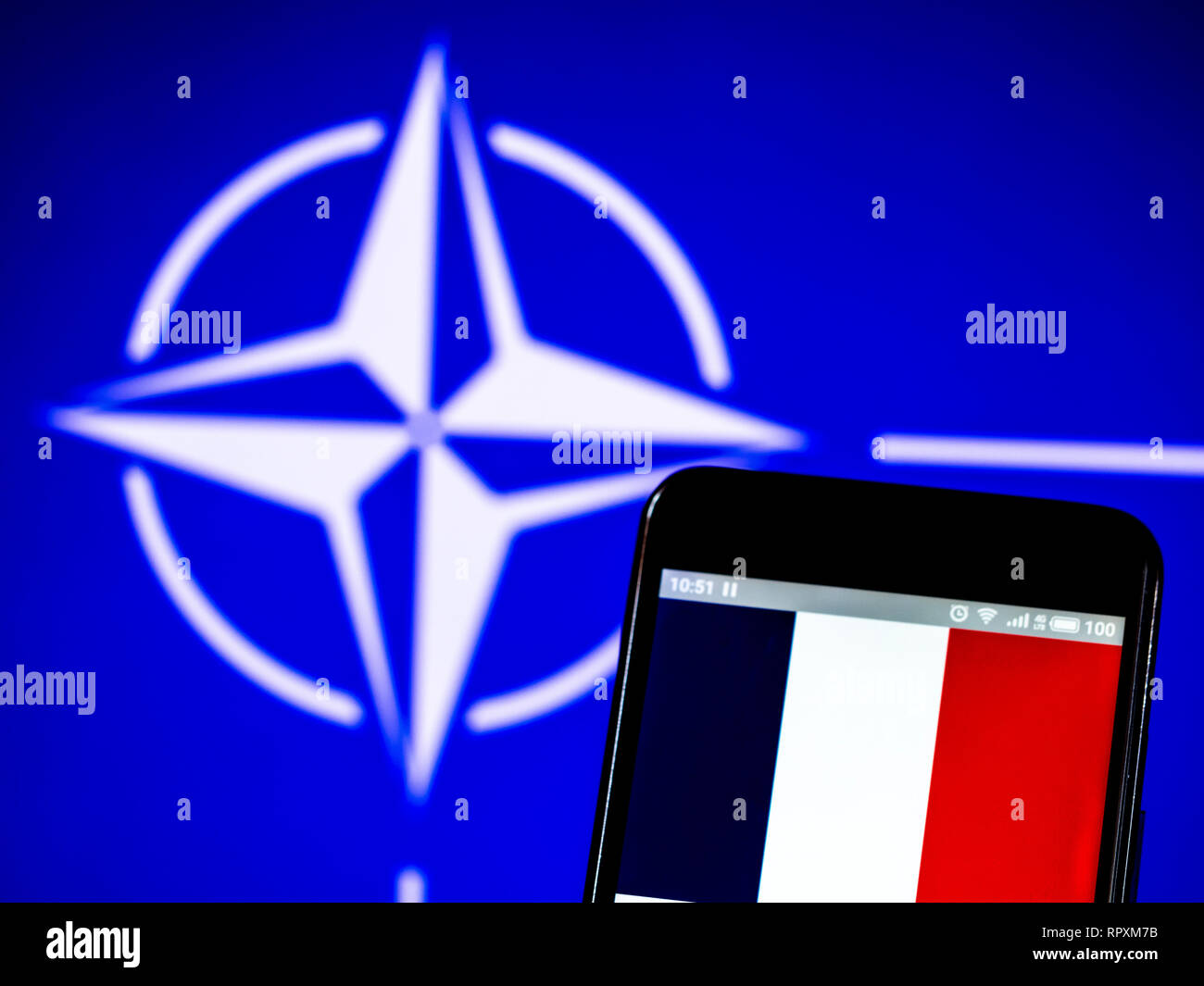 Bandiera della Francia sul display del telefono cellulare sullo sfondo  della bandiera della NATO Foto stock - Alamy