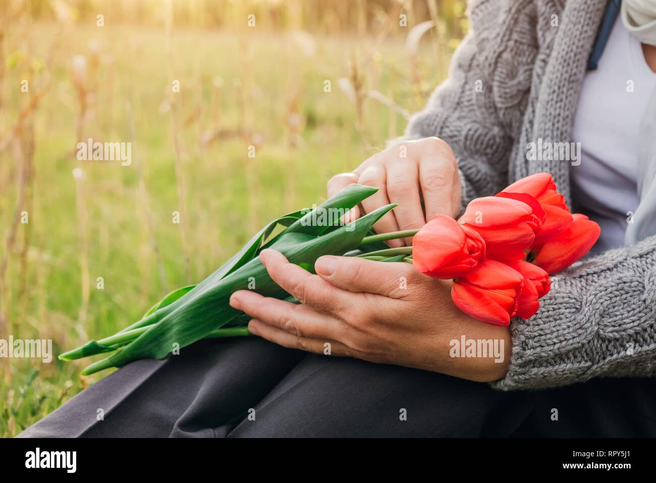 La donna tiene un bouquet di tulipani rossi al di fuori. Foto Stock