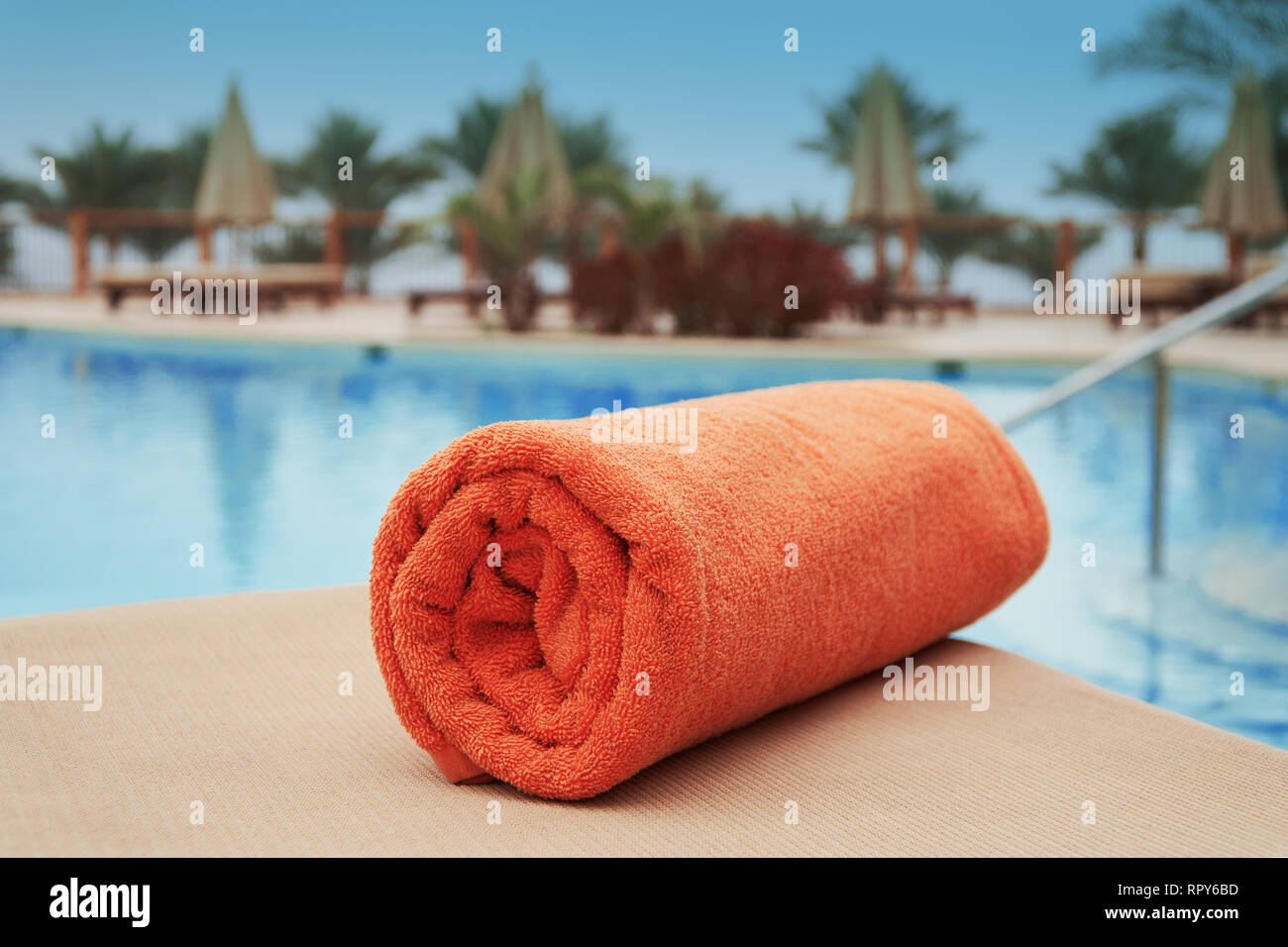 Asciugamano arancione sdraiato su un lettino vicino alla piscina piscina hotel estate Foto Stock