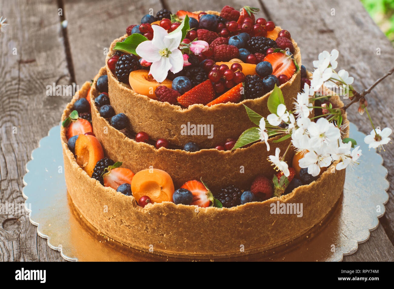 Cheesecake con frutti e bacche sul vecchio plance, bianco apple e fiori di ciliegio Foto Stock