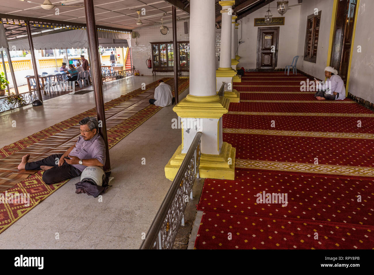Gli uomini rilassante a metà pomeriggio all'ombra della moschea di Hulu, Masjid Hulu, Melaka, Malaysia. Foto Stock