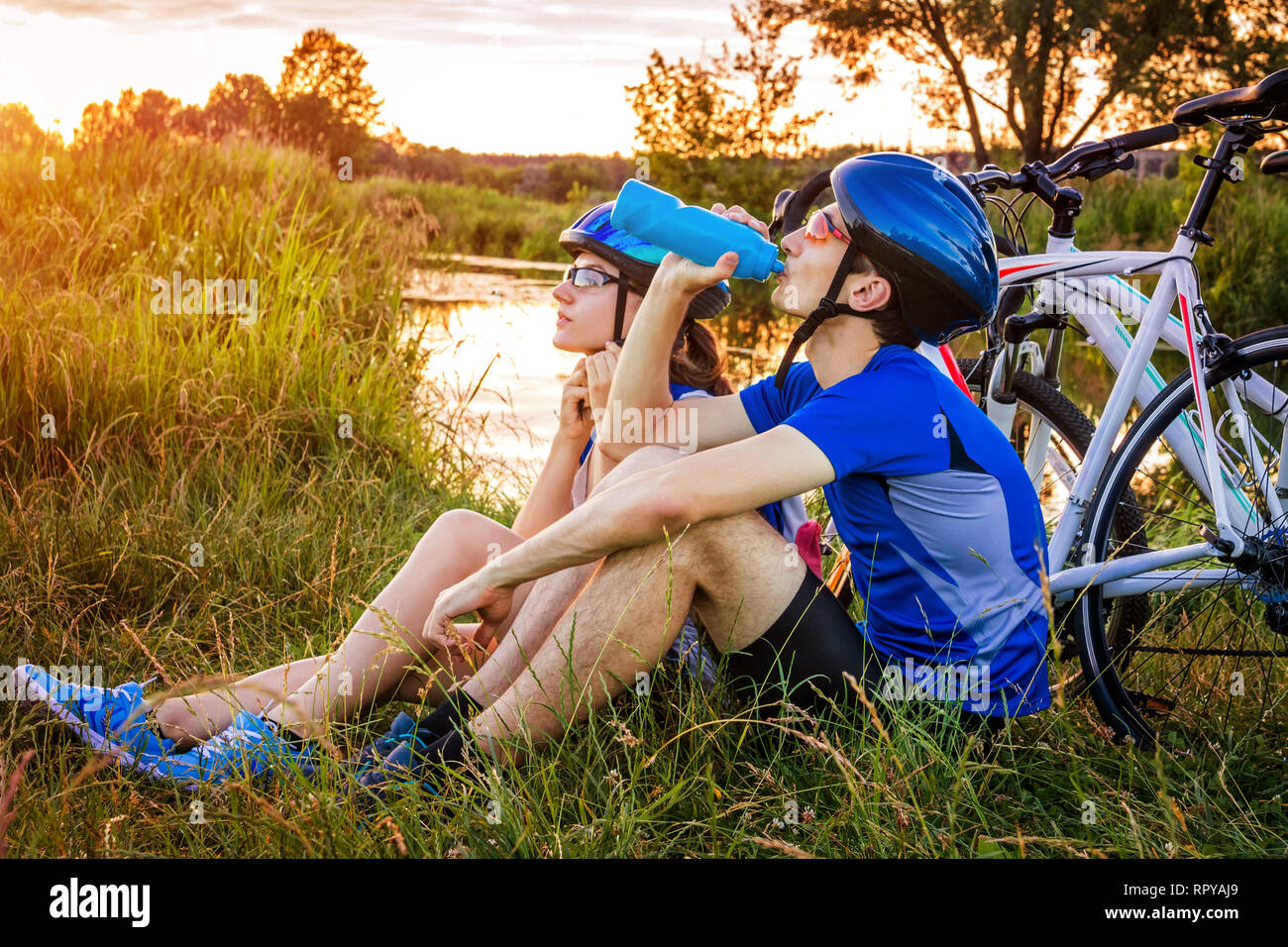 Paio di ciclisti avente il resto dal fiume al tramonto Foto Stock