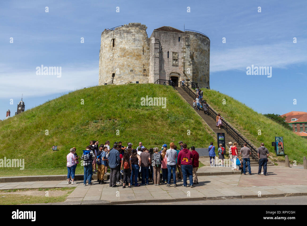 Un gruppo turistico di fronte la Torre di Clifford, città di York, nello Yorkshire, Regno Unito. Foto Stock