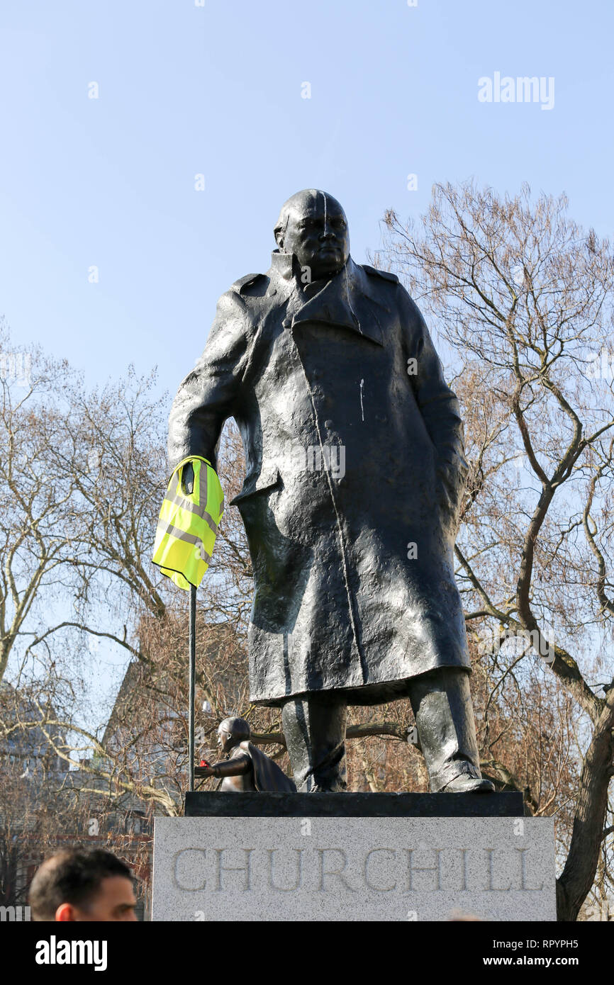 Londra, Regno Unito. Il 23 febbraio, 2019. Winston Churchills statua in piazza del Parlamento ha un giubbotto giallo gettato sopra la sua mano. Giubbotto giallo REGNO UNITO soddisfi a Trafalgar Square per una giornata di azione e in giro per le strade di Westminster. Penelope Barritt/Alamy Live News Foto Stock