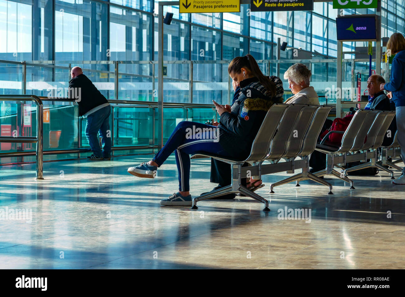 Seduto viaggiatore femmina guardando al telefono, in attesa aeroporto di Alicante, Alicante, Valencia Provence, Spagna, Europa Foto Stock