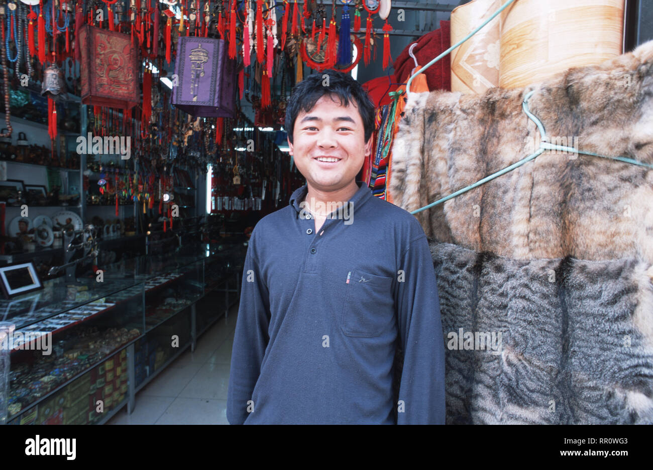 Un tibetano uomo in piedi fuori il suo gingillo e pelle non conciata shop in Kangding, una piccola cittadina a formare il confine tra la Cina e il Tibet nel Sichuan. Nonostante il Foto Stock