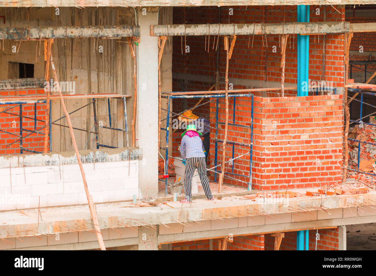 Muratore lavoratore di sesso femminile che di lavoro installazione industriale di mattoni della parete nel sito in costruzione Foto Stock