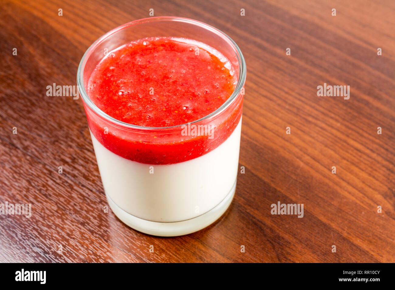 Fragola panna cotta dessert in un vetro isolato su una tavola di legno ricetta idea Foto Stock