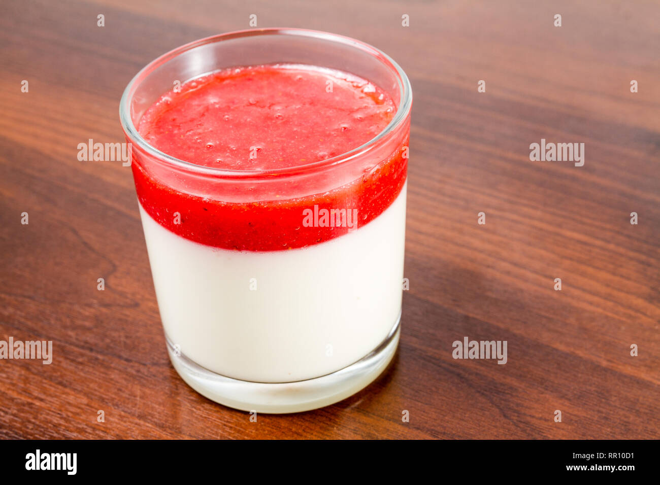 Fragola panna cotta dessert in un vetro isolato su una tavola di legno ricetta idea Foto Stock