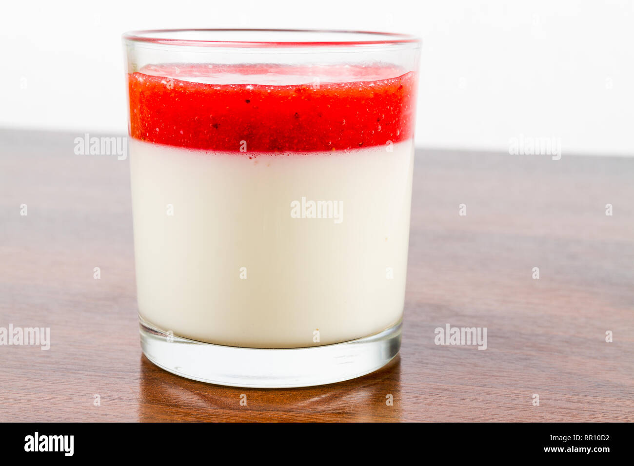Fragola panna cotta dessert in un vetro isolato su una tavola di legno ricetta idea Foto Stock