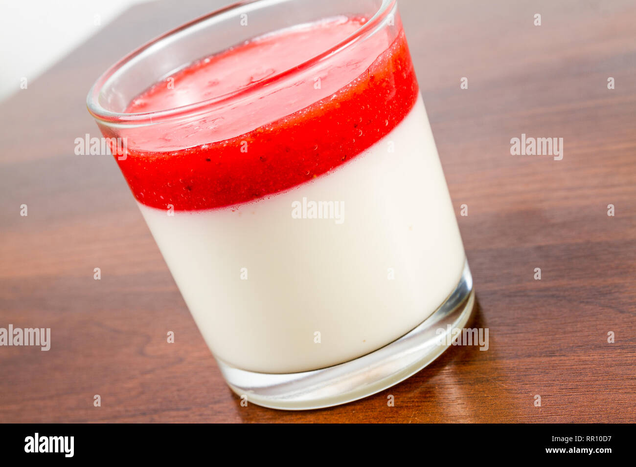 Fragola panna cotta dessert in un vetro isolato su una tavola di legno ricetta idea Foto Stock