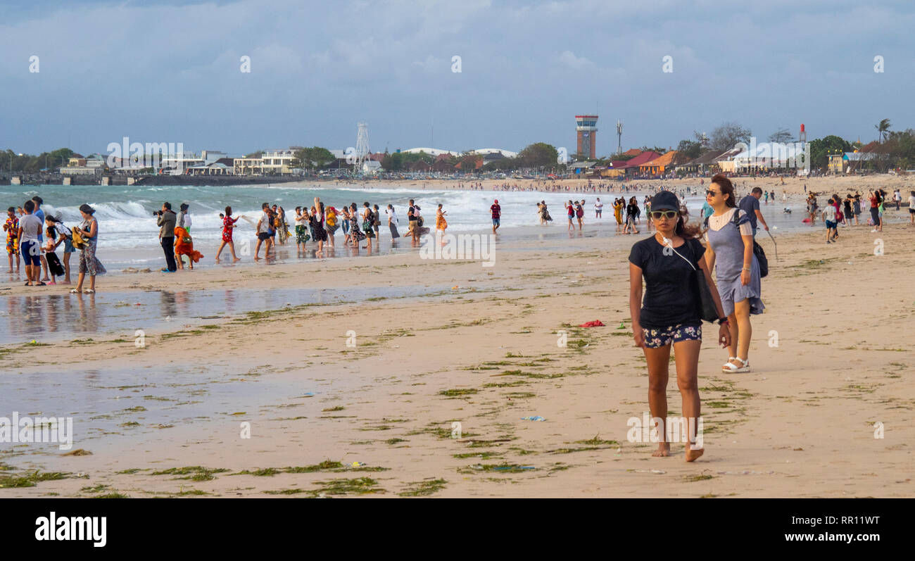 I turisti cinesi in vacanza in vacanza in spiaggia al tramonto nella Baia di Jimbaran Bali Indonesia Foto Stock