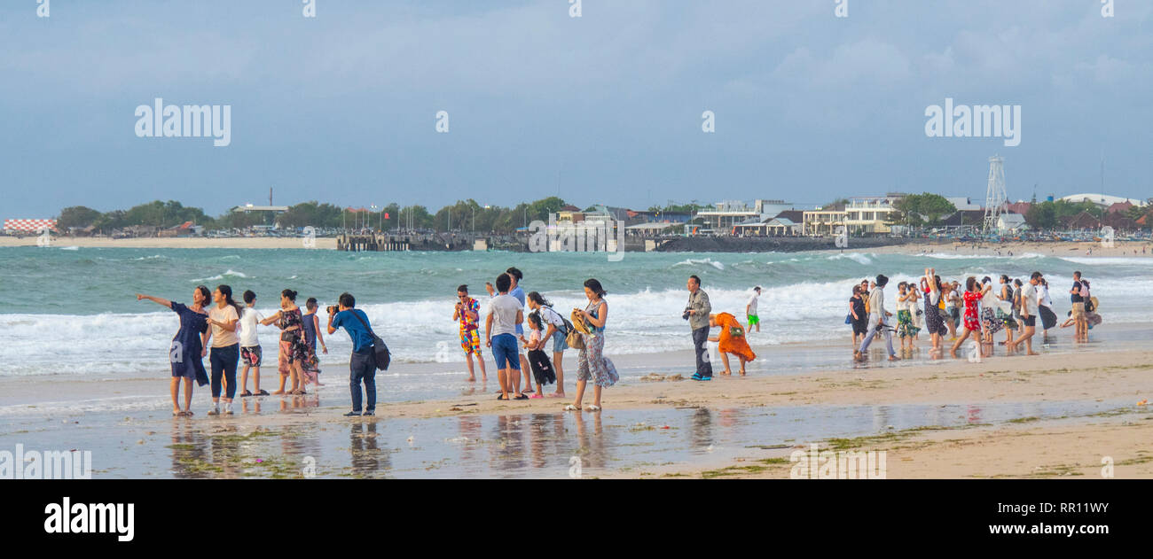 I turisti cinesi in vacanza in vacanza in spiaggia al tramonto nella Baia di Jimbaran Bali Indonesia Foto Stock