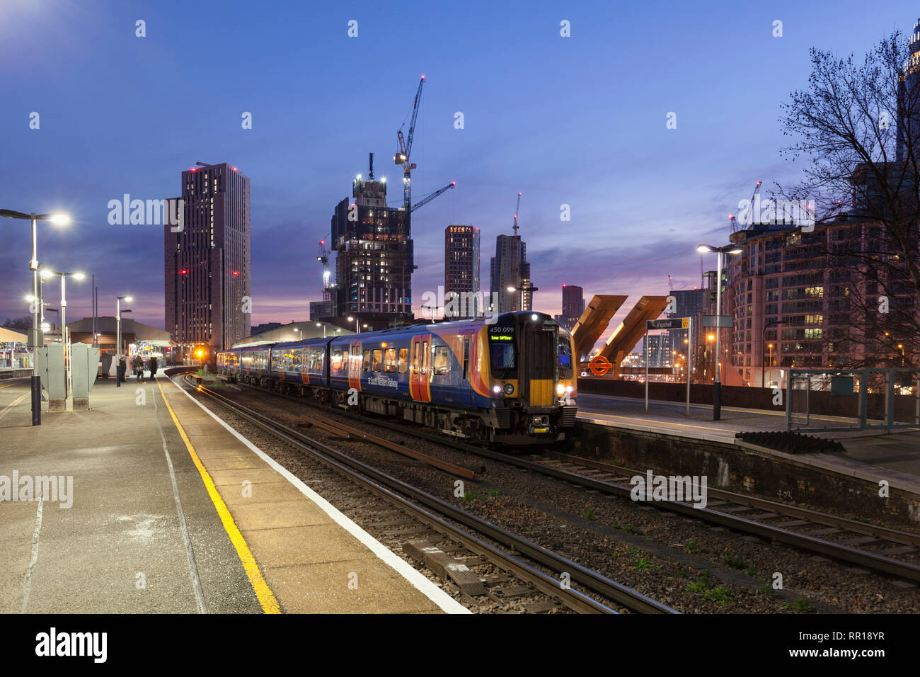 2 South Western Railway classe 450 EMU chiamata alla stazione di Vauxhall di Londra con la skyline di Londra dietro al crepuscolo Foto Stock