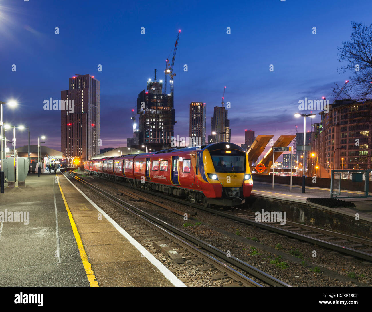 Un Sud Occidentale classe ferroviaria 707 chiamando alla Vauxhall, Londra al tramonto con la skyline di Londra dietro Foto Stock