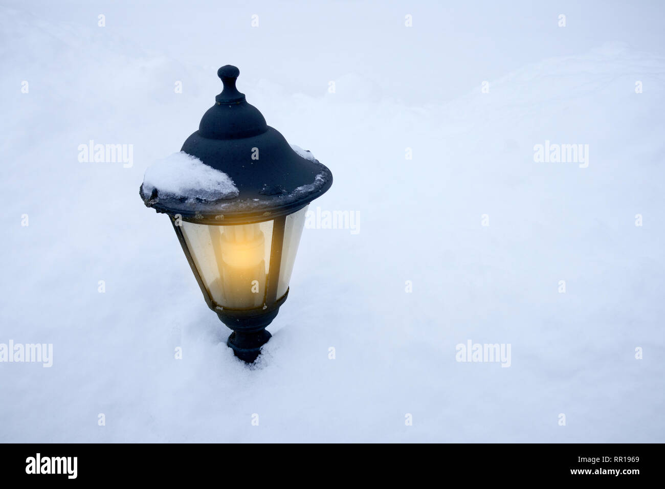 Metallo vecchia strada illuminata lampada situata su un campo di neve outdoor Foto Stock