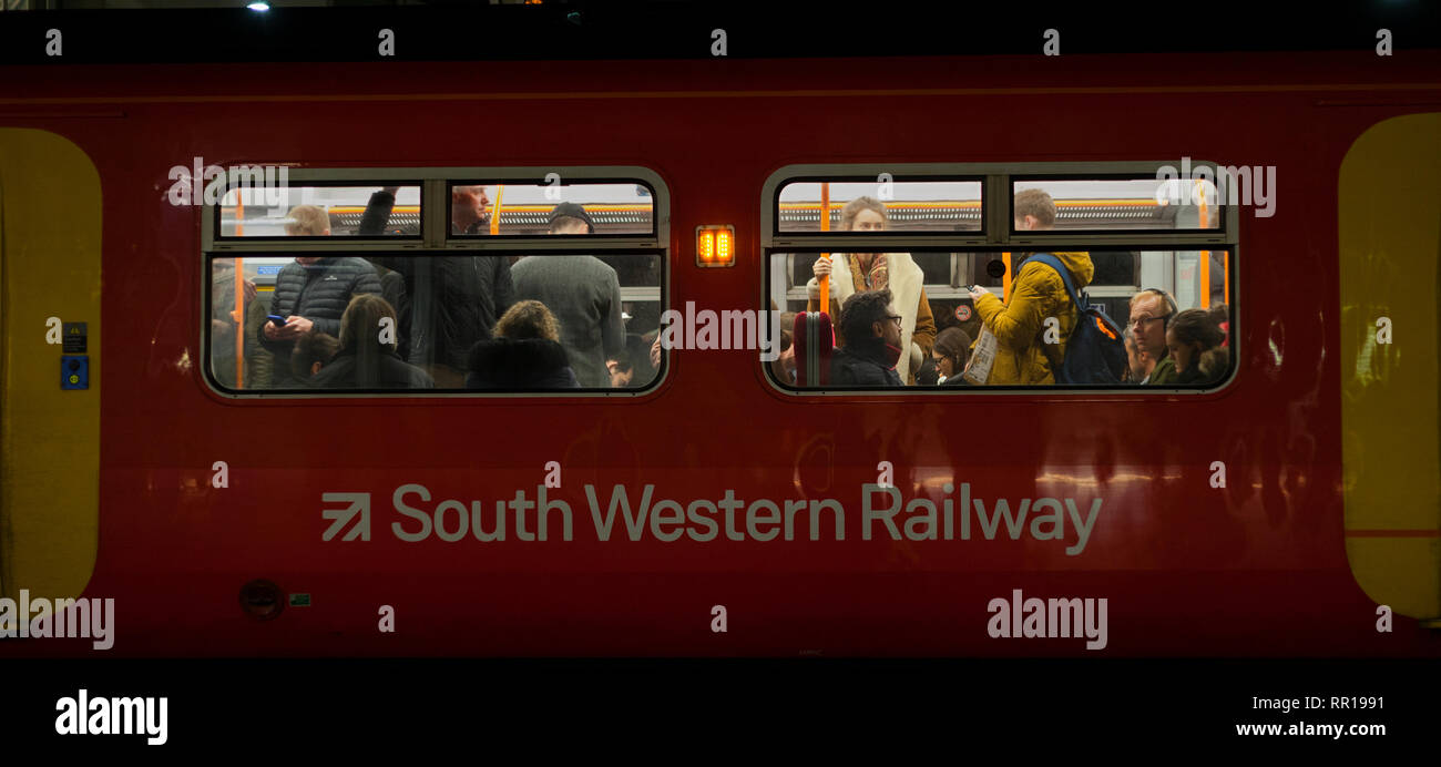 Rail Pendolari su un affollato sud occidentale del treno Ferrovie voce lontano da Londra a Clapham Junction in serata Rush Hour Foto Stock