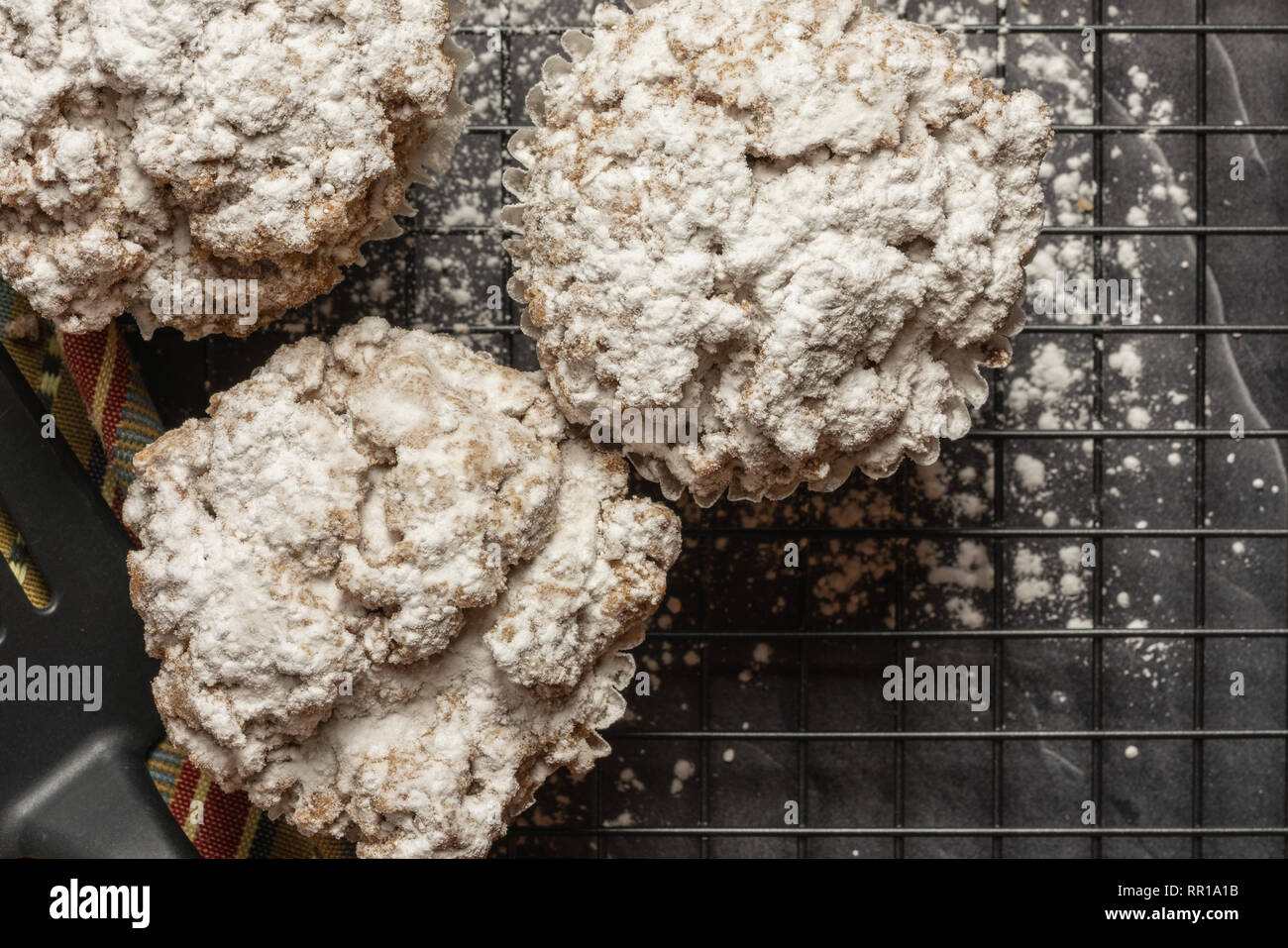 Vista ravvicinata di cannella mollica muffin su una griglia di raffreddamento seduto su un banco di marmo nero con una spatola e igienico Foto Stock