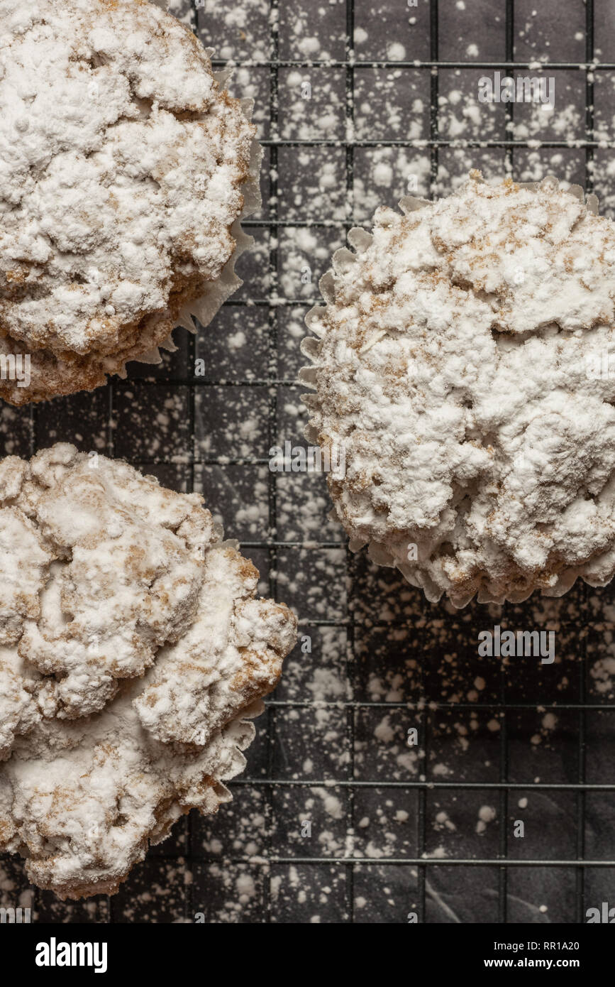 Tre cannella mollica muffin su una cremagliera con zucchero a velo sul marmo nero verticale da banco Foto Stock
