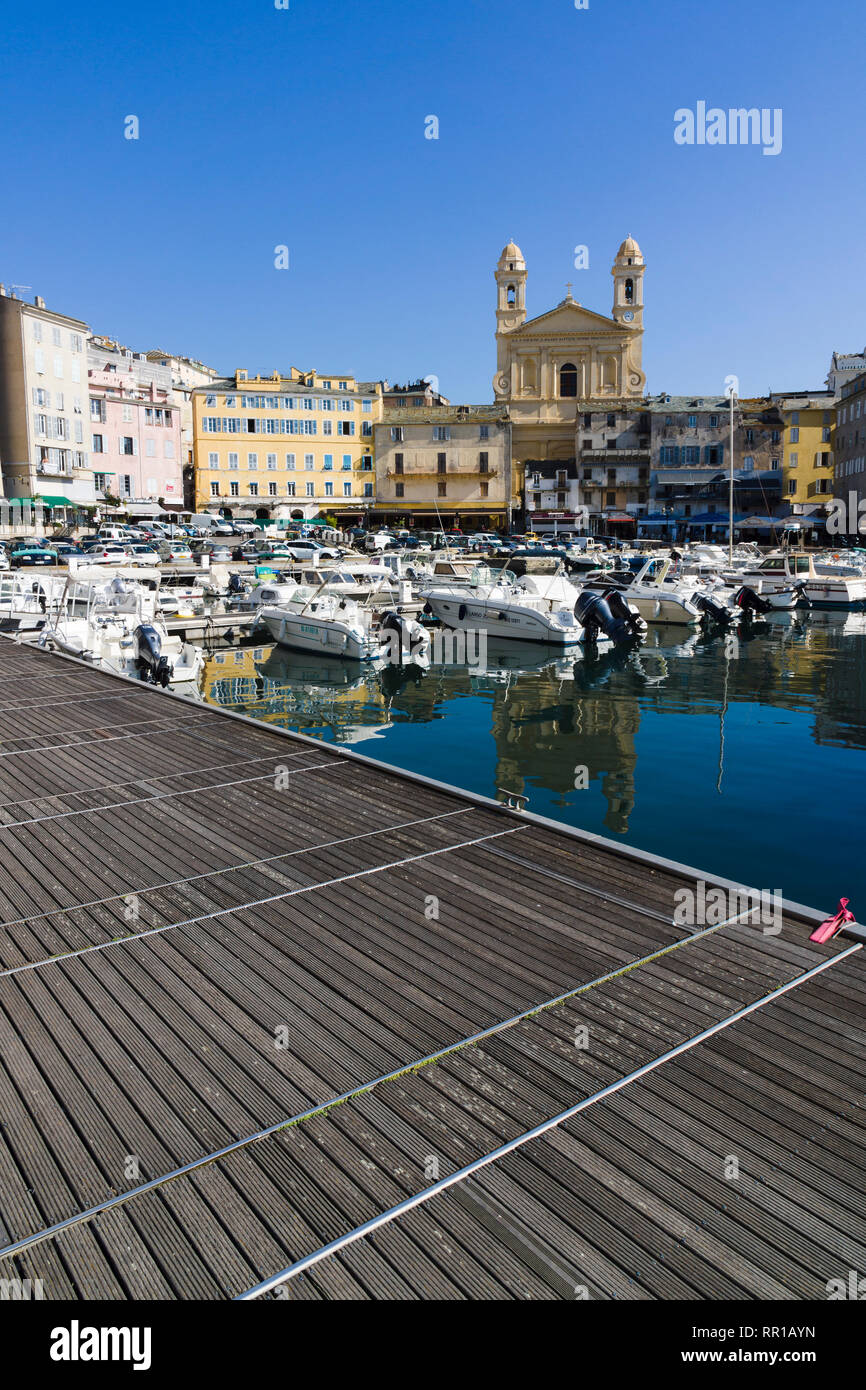 Molo di legno che si affaccia su barche ormeggiate nel Vieux Port con la chiesa di Saint-Jean-Baptiste sullo sfondo, Bastia, Corsica, Francia. Foto Stock